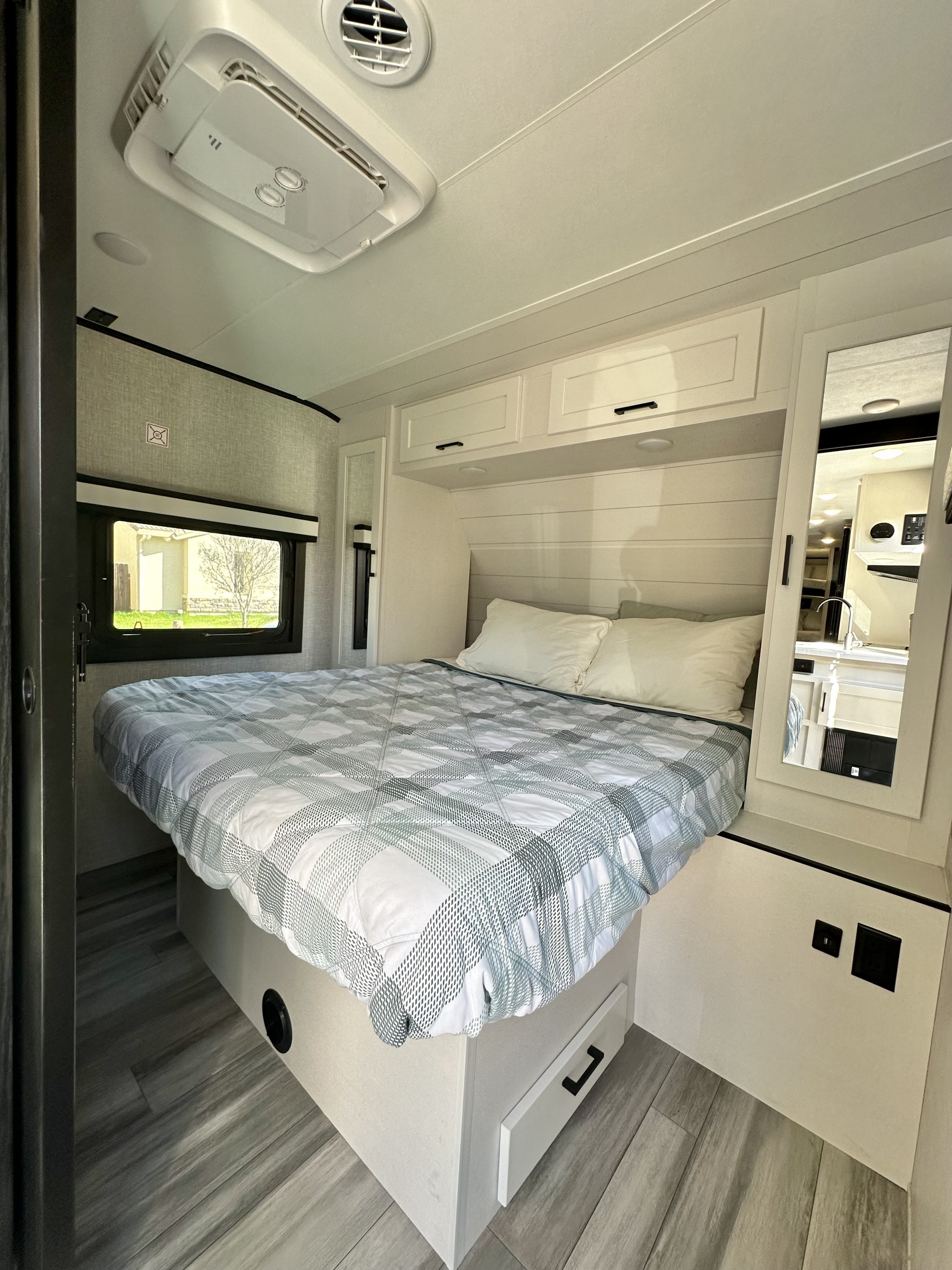 Modern RV rental bedroom interior with a comfortable bed, storage, AC, and window. Ideal for travel.. Jayco Jay Feather 2024