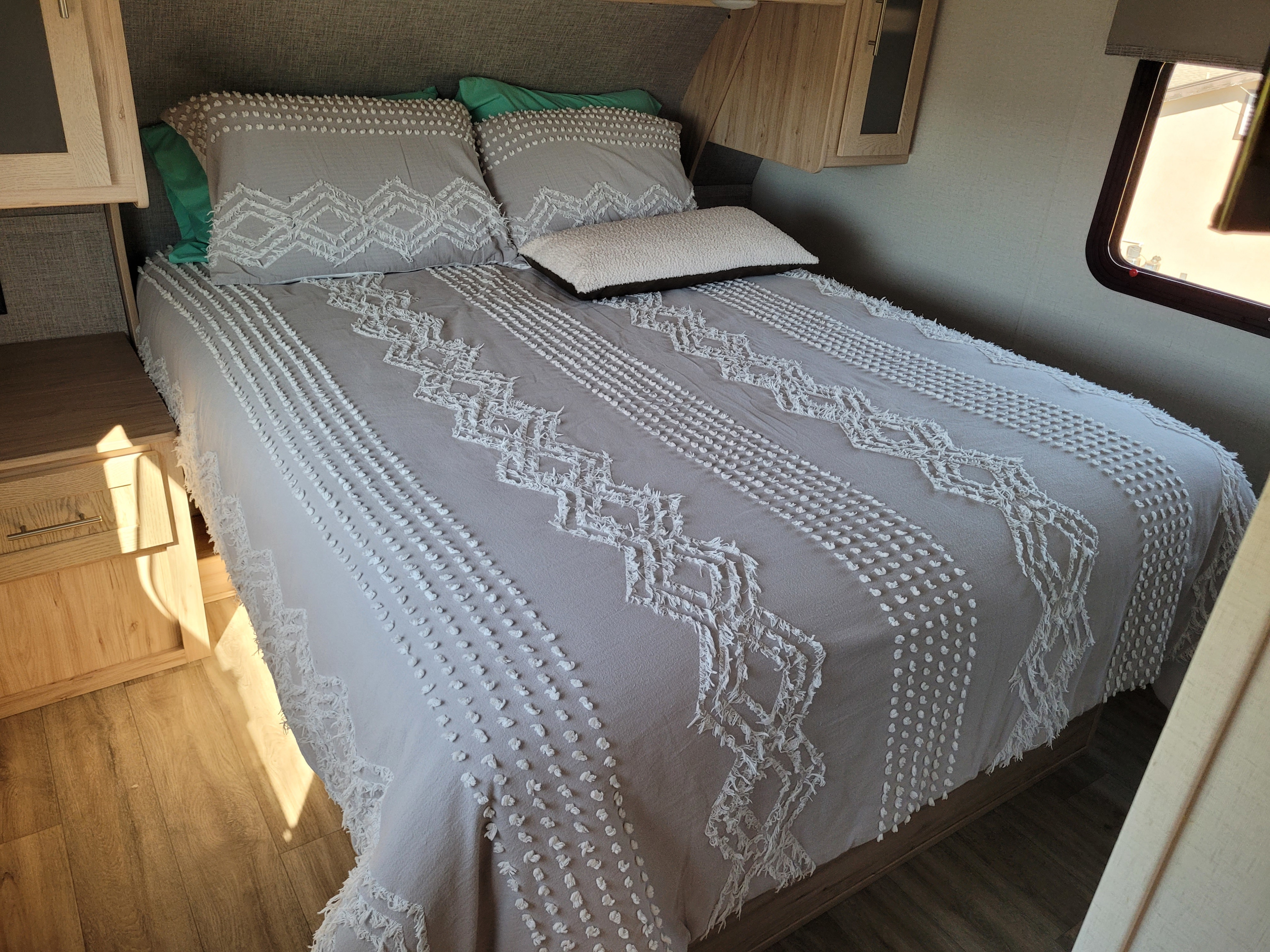 Cozy RV rental bedroom featuring a bed with stylish gray and white textured bedding and built-in wooden cabinetry.. Alliance RV Avenue All Access 2023