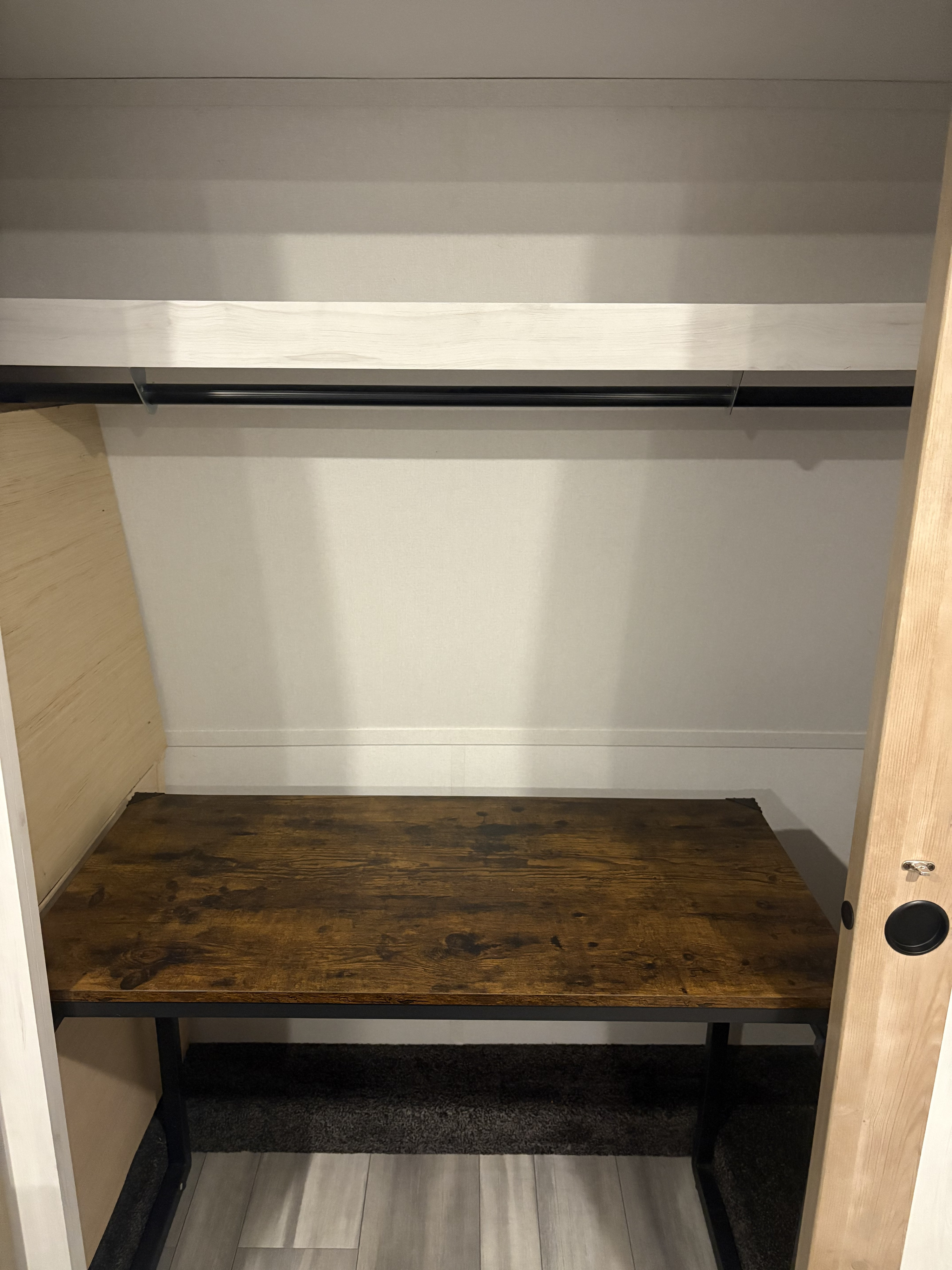 RV rental bedroom/closet: a built-in desk with a dark wood top, overhead shelf, and hanging rod offer versatile storage and workspace.. Heartland RVs Milestone 2024
