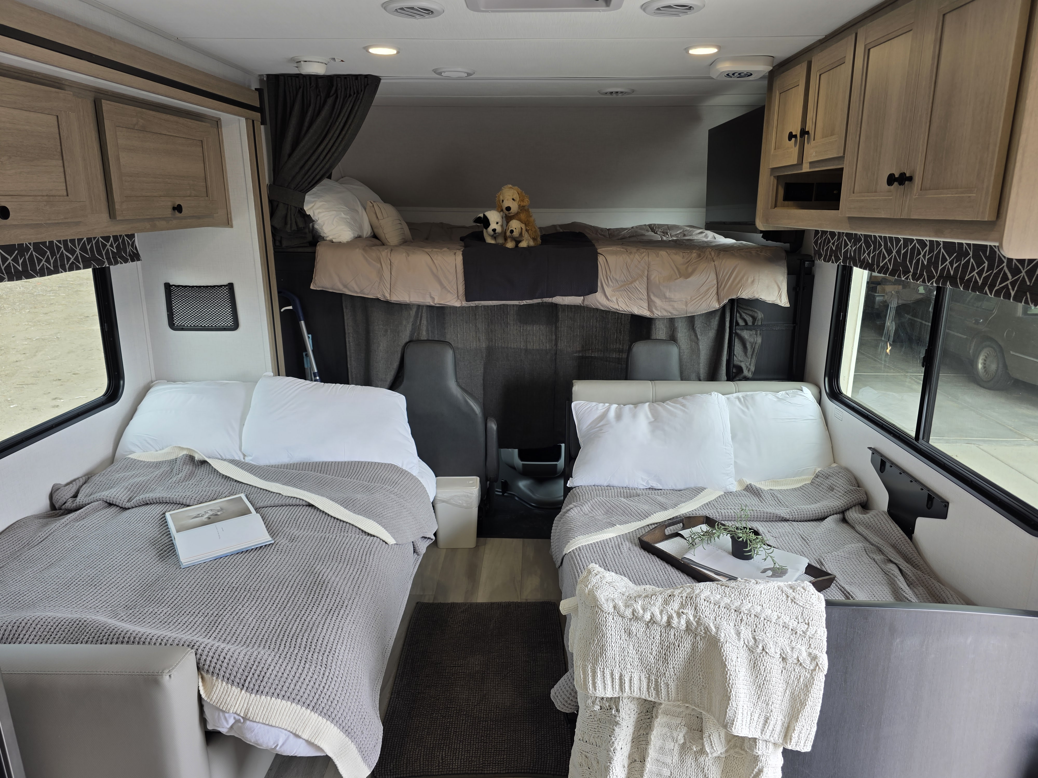 Inside a spacious RV rental, featuring two lower beds, an overhead bunk with stuffed animals, and warm wooden cabinetry.. Forest River Sunseeker Classic 2025