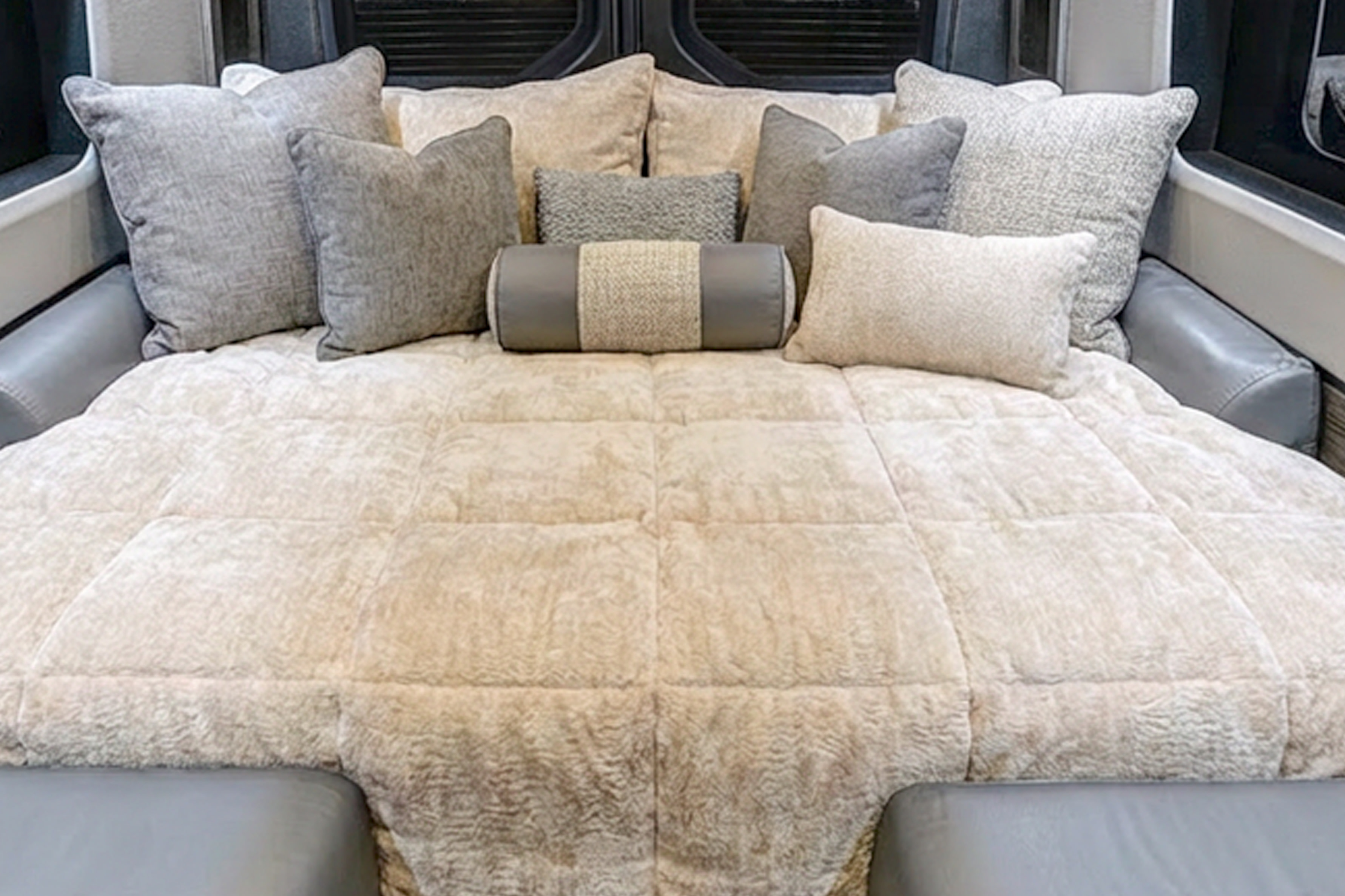 Cozy RV rental bed with neutral pillows and a textured comforter, creating an inviting, comfortable travel space.. Grech Strada Ion Mercedes Sprinter 2025