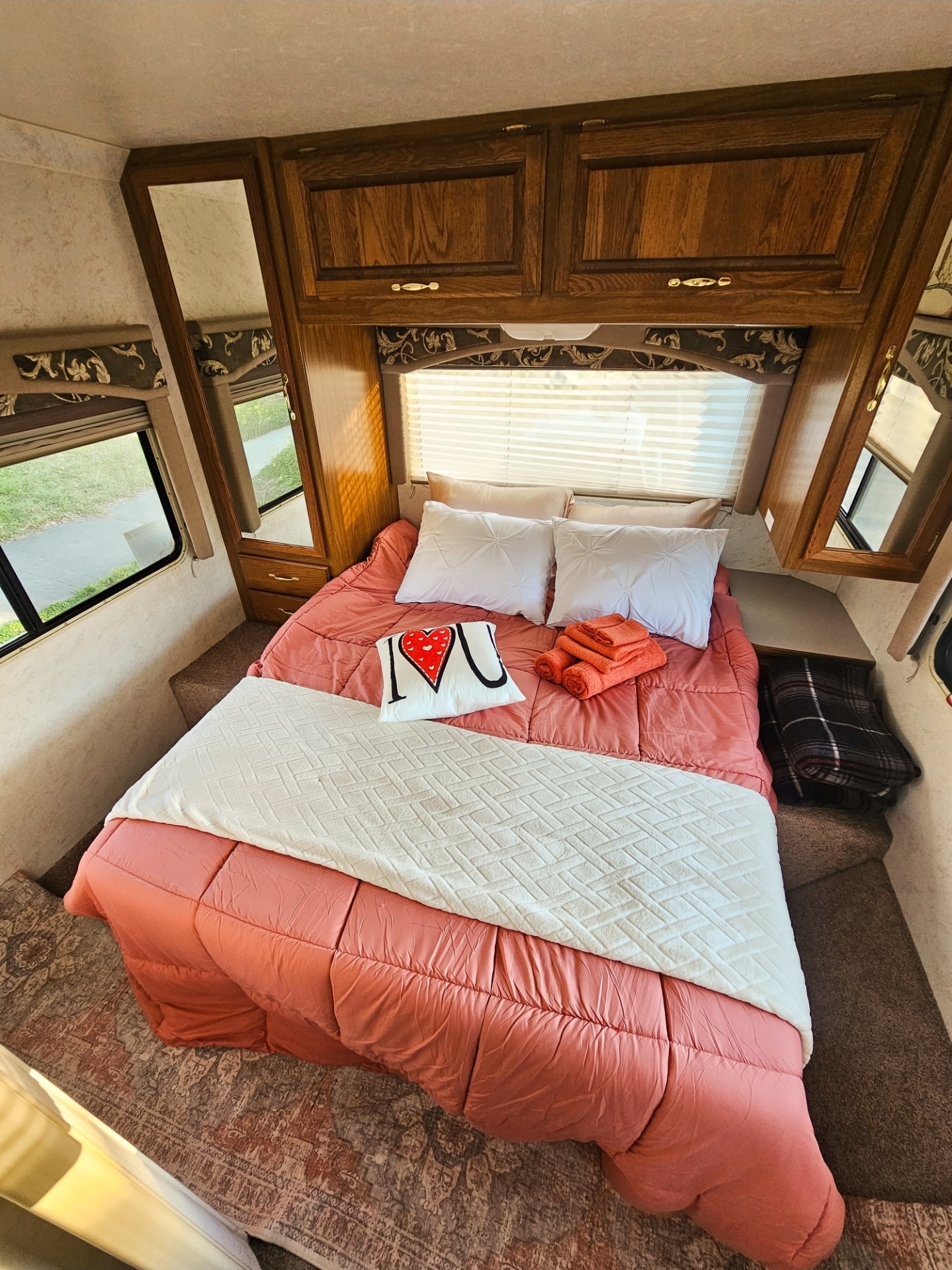 Cozy RV rental bedroom with coral bedding, white pillows & blanket, plus wooden accents & windows. Ideal for road trips!. Thor Motor Coach 31E 2002