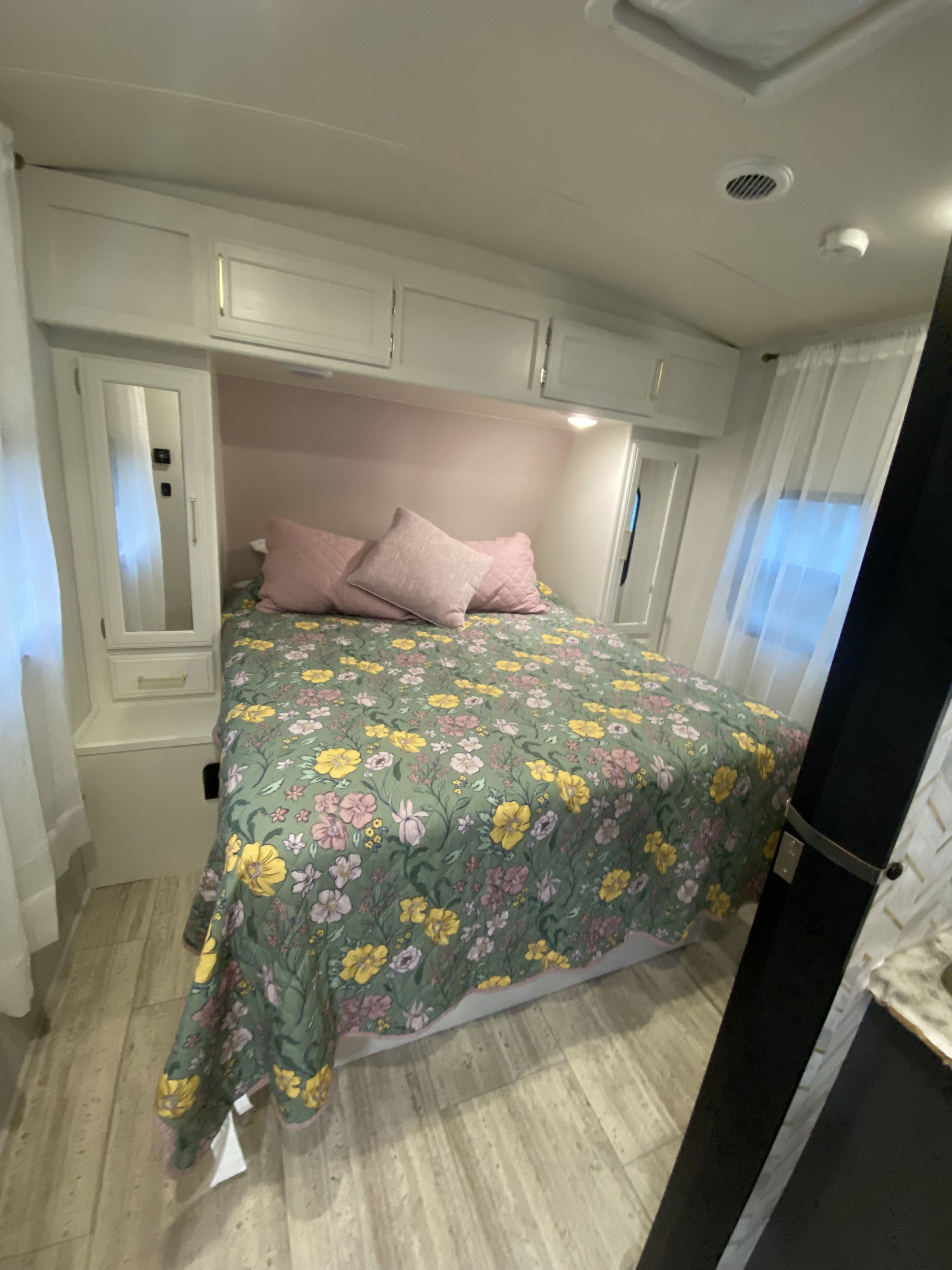 This inviting RV rental bedroom showcases a cheerful floral quilt, soft pink pillows, and practical built-in storage.. Grand Design Imagine 2017