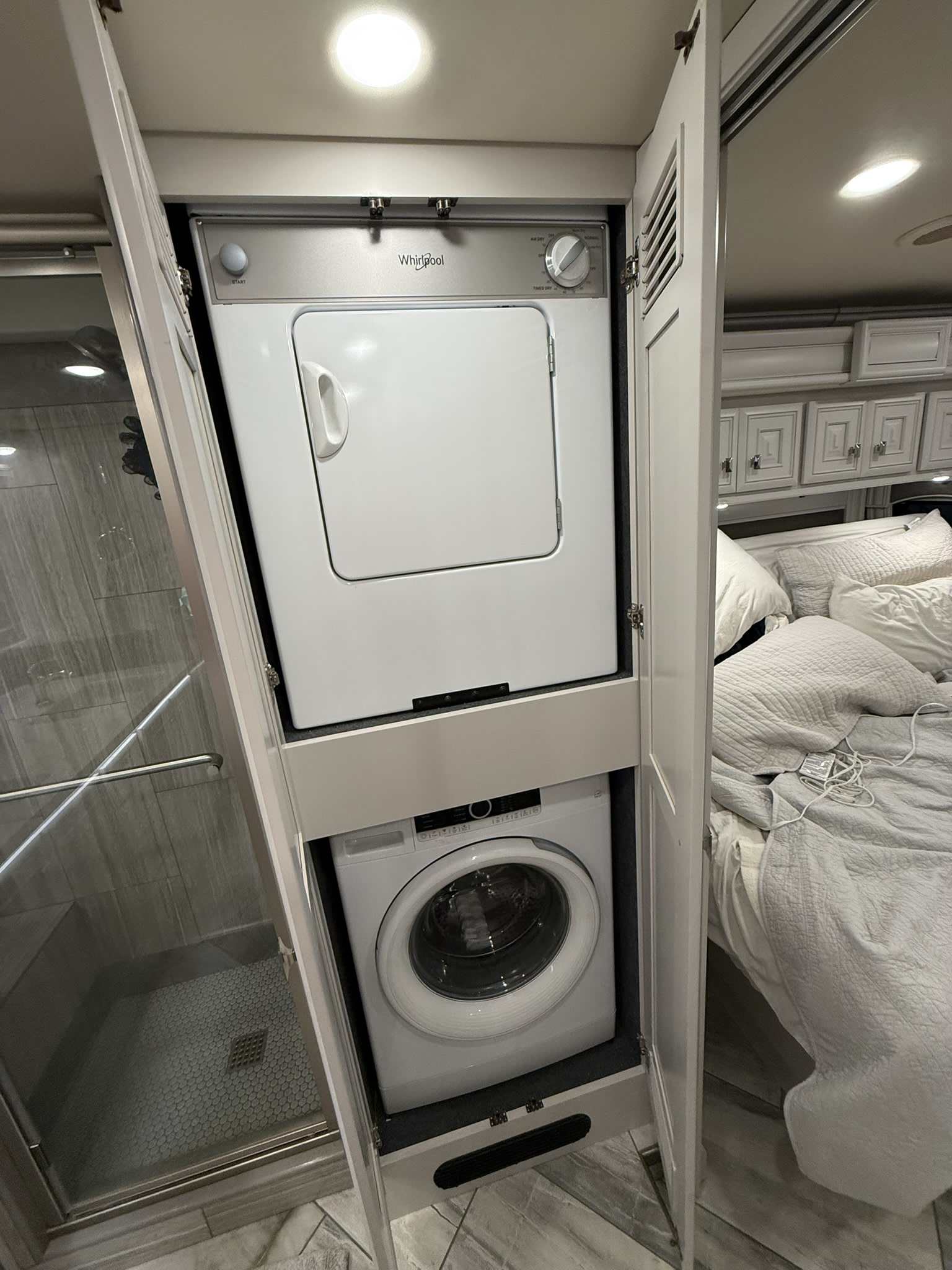 This RV rental boasts a stacked Whirlpool washer/dryer, tucked between the modern shower and cozy bedroom area.. Fleetwood Discovery LXE 2021
