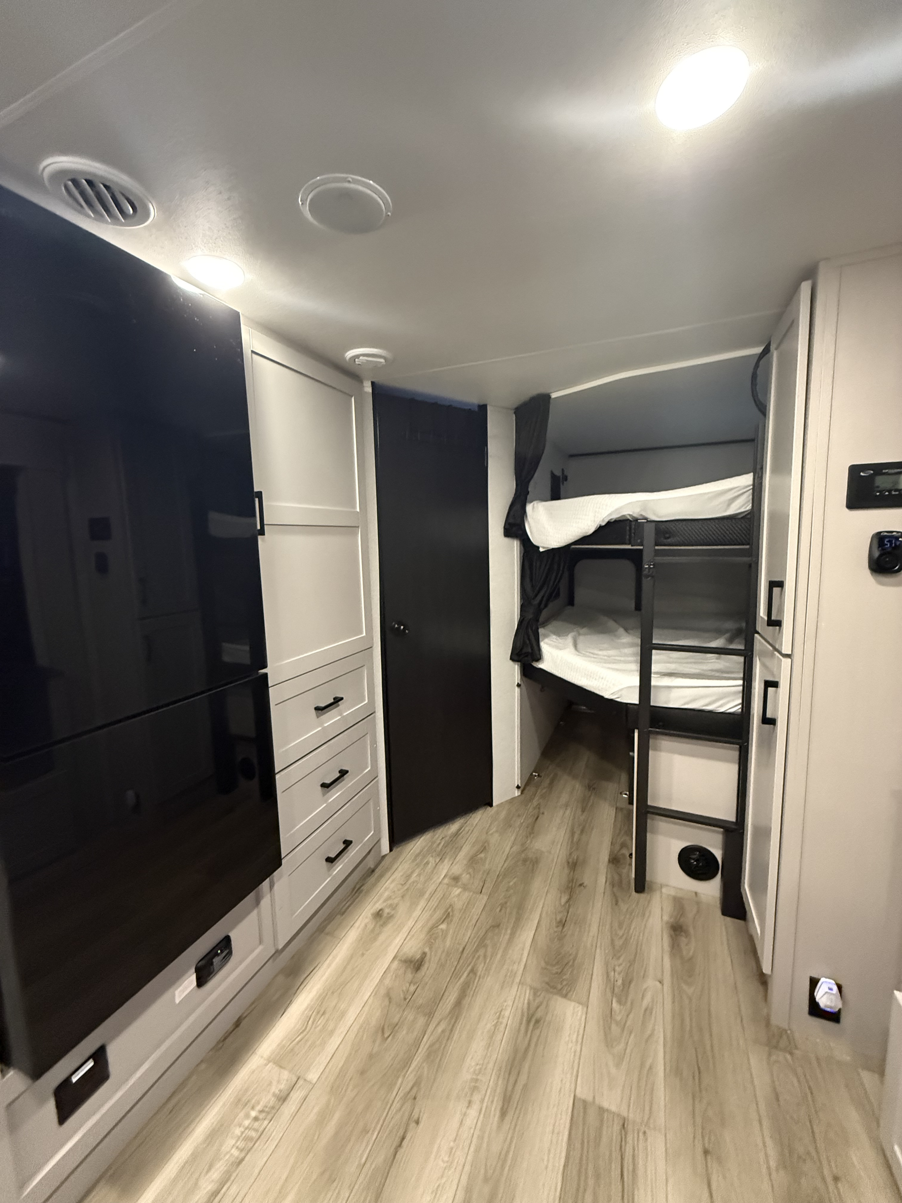This RV rental interior features sleek black & white cabinets, cozy bunk beds, and wood flooring, ideal for a family getaway.. Jayco Jayfeather 2026