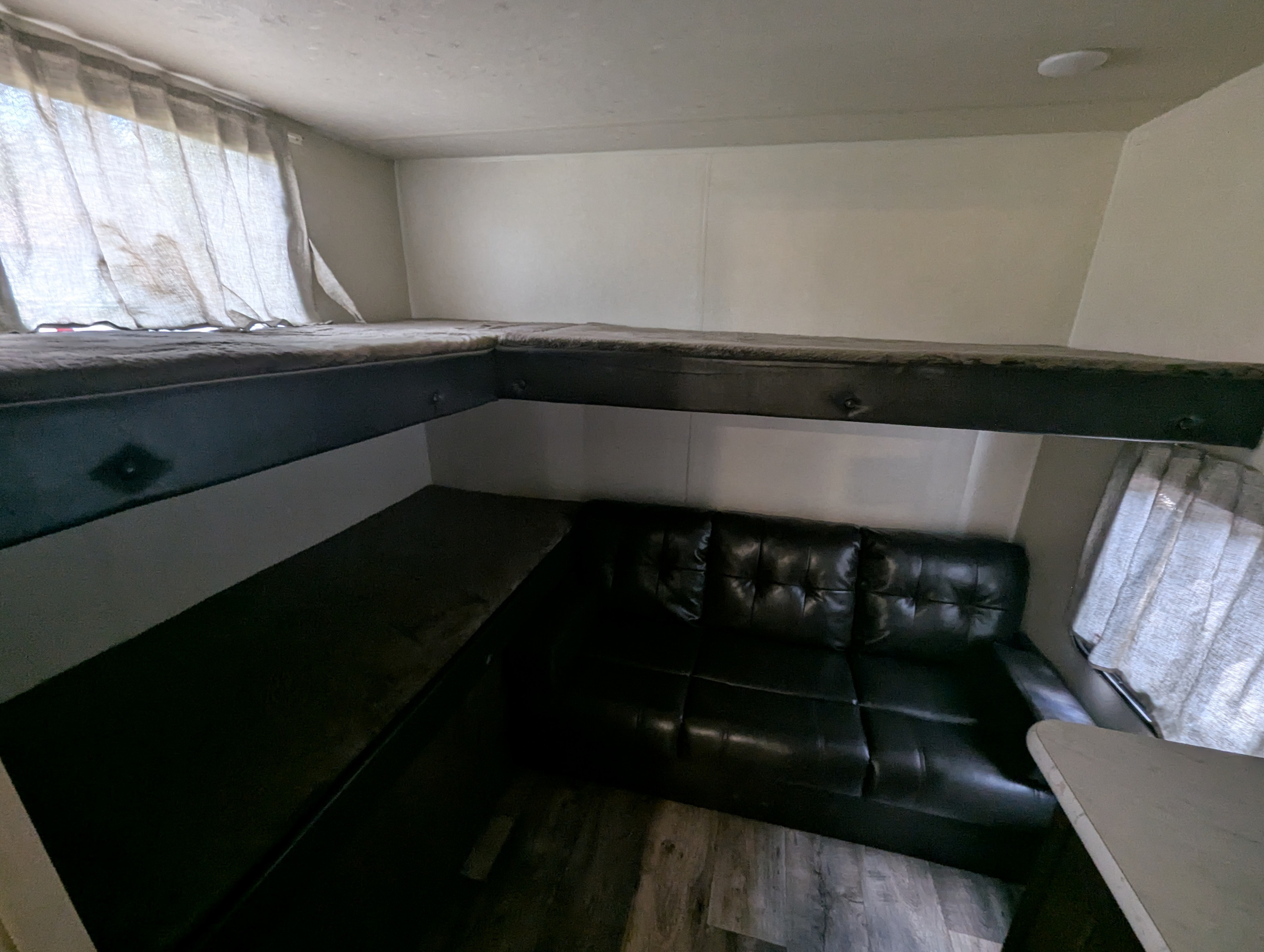 Inside an rv rental: L-shaped bunk beds above dark sofa and cushioned seating with windows for light, optimizing small space.. Forest River Salem Cruise Lite 2018