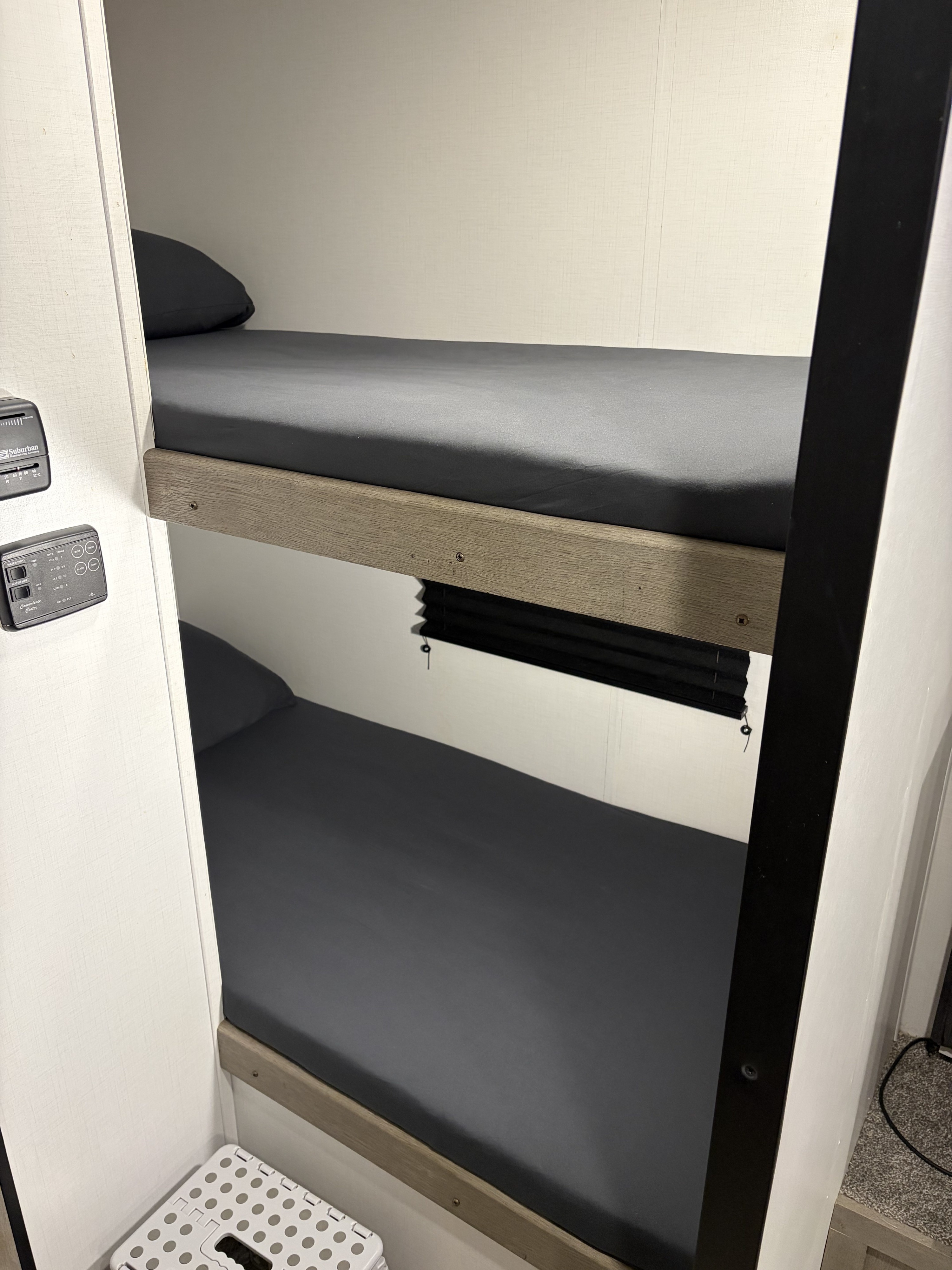 Comfortable bunk beds in this RV rental, complete with control panels and a handy step stool for easy access.. Keystone RV Springdale 2021