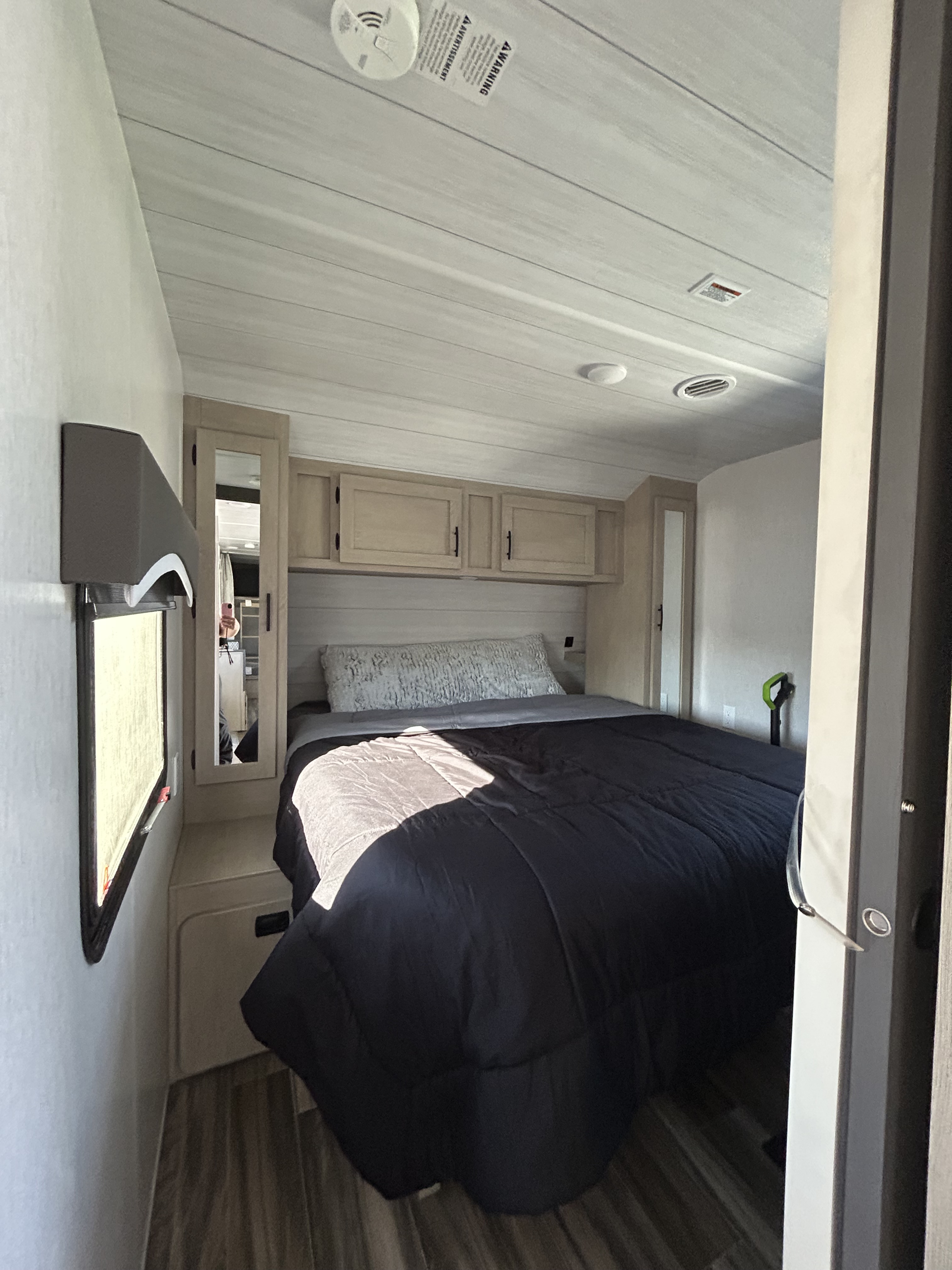 Inside an RV rental: a cozy bedroom with a dark comforter, light wood cabinets, and an AC vent. Perfect for camping adventures.. Forest River Evo T2650 2023