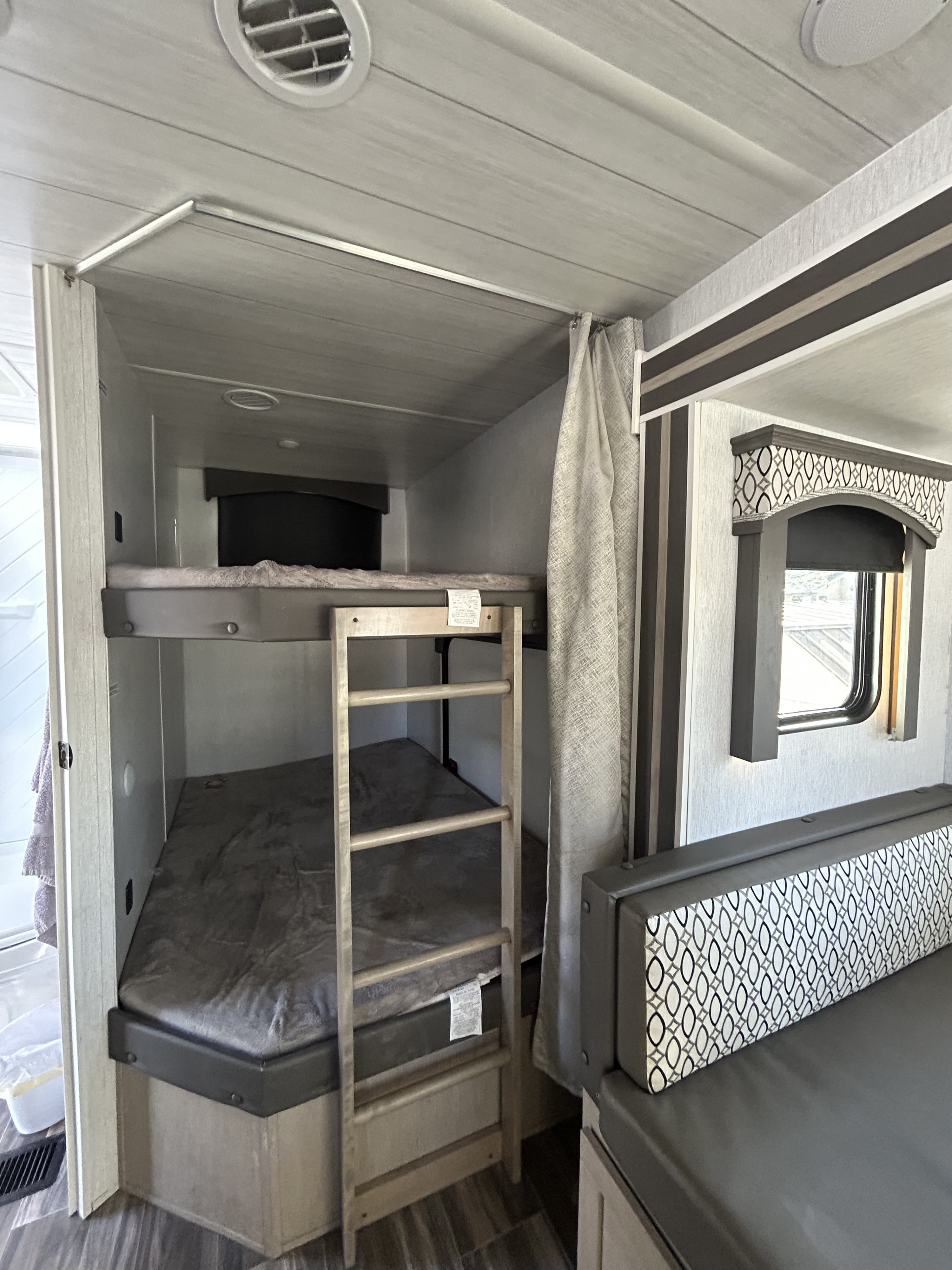 RV rental interior: cozy bunk beds with ladder, alongside a dinette and window, ideal for family travel.. Forest River Evo T2650 2023