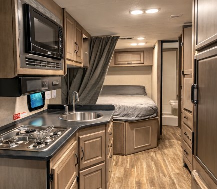 Compact RV rental interior with kitchen, microwave, bed, and bathroom, perfect for your next adventure.. Thor Majestic 2020