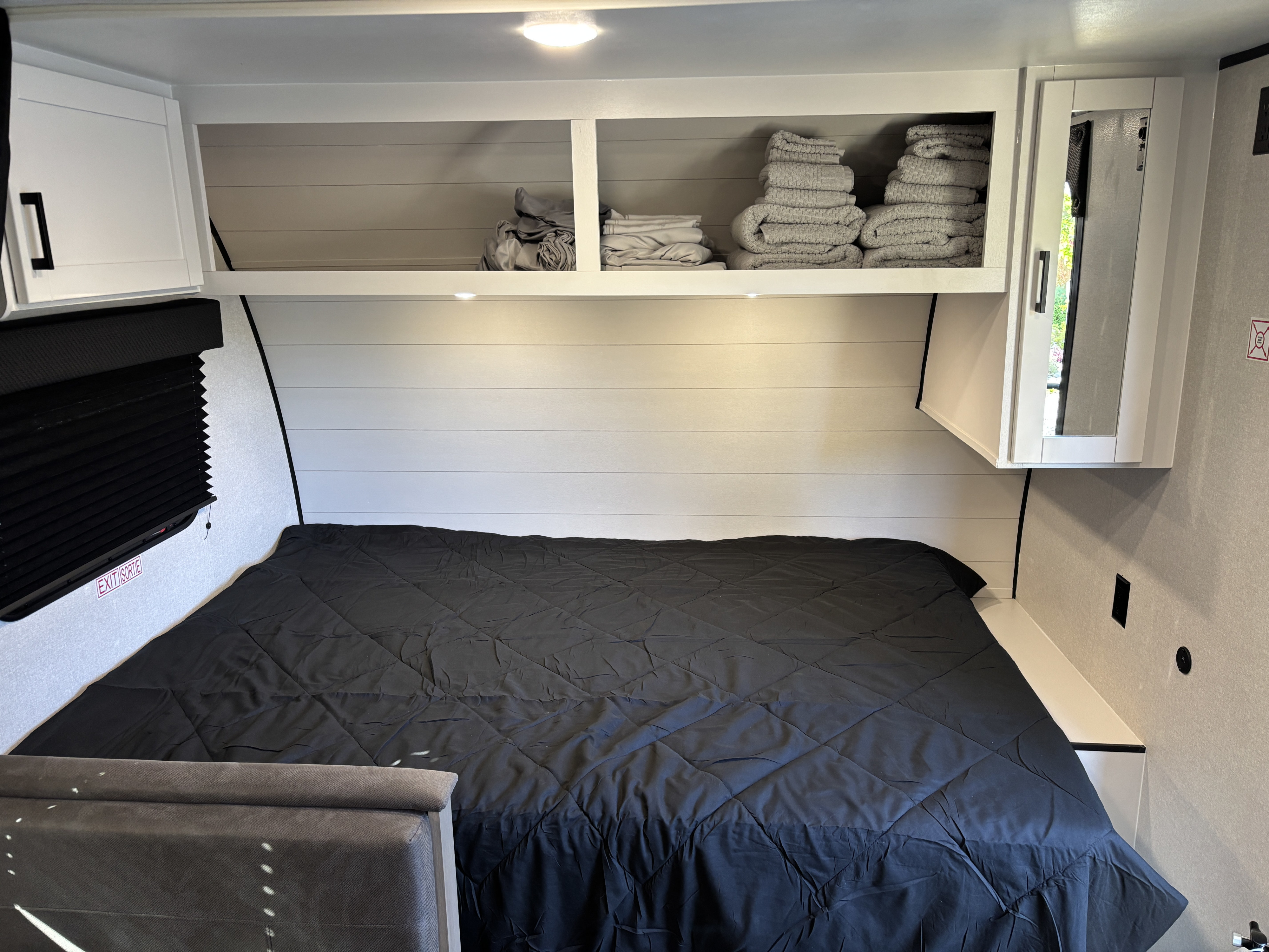 Cozy RV rental bedroom featuring a comfortable bed, ample overhead storage, and stylish shiplap walls.. Jayco JayFlight 2026