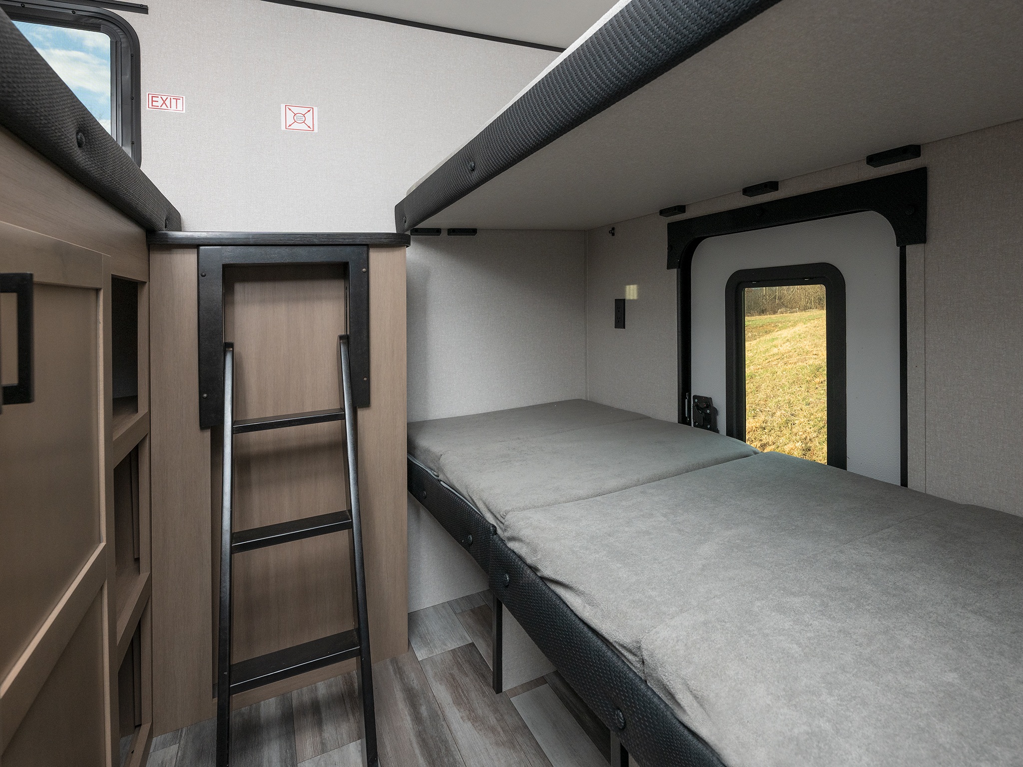 RV rental interior: lower bunk with gray mattress, upper bunk, access ladder, emergency exit, and window view.. Jayco Jay Flight 2026