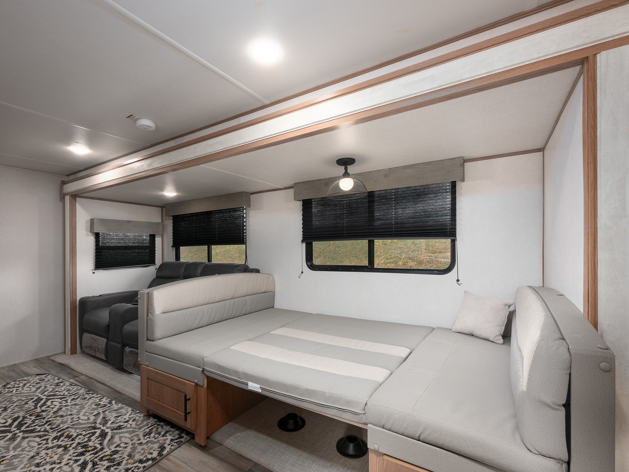 Cozy RV rental interior with a convertible bed, recliners, and ample lighting, perfect for comfortable journeys.. Prime Time Avenger 2024