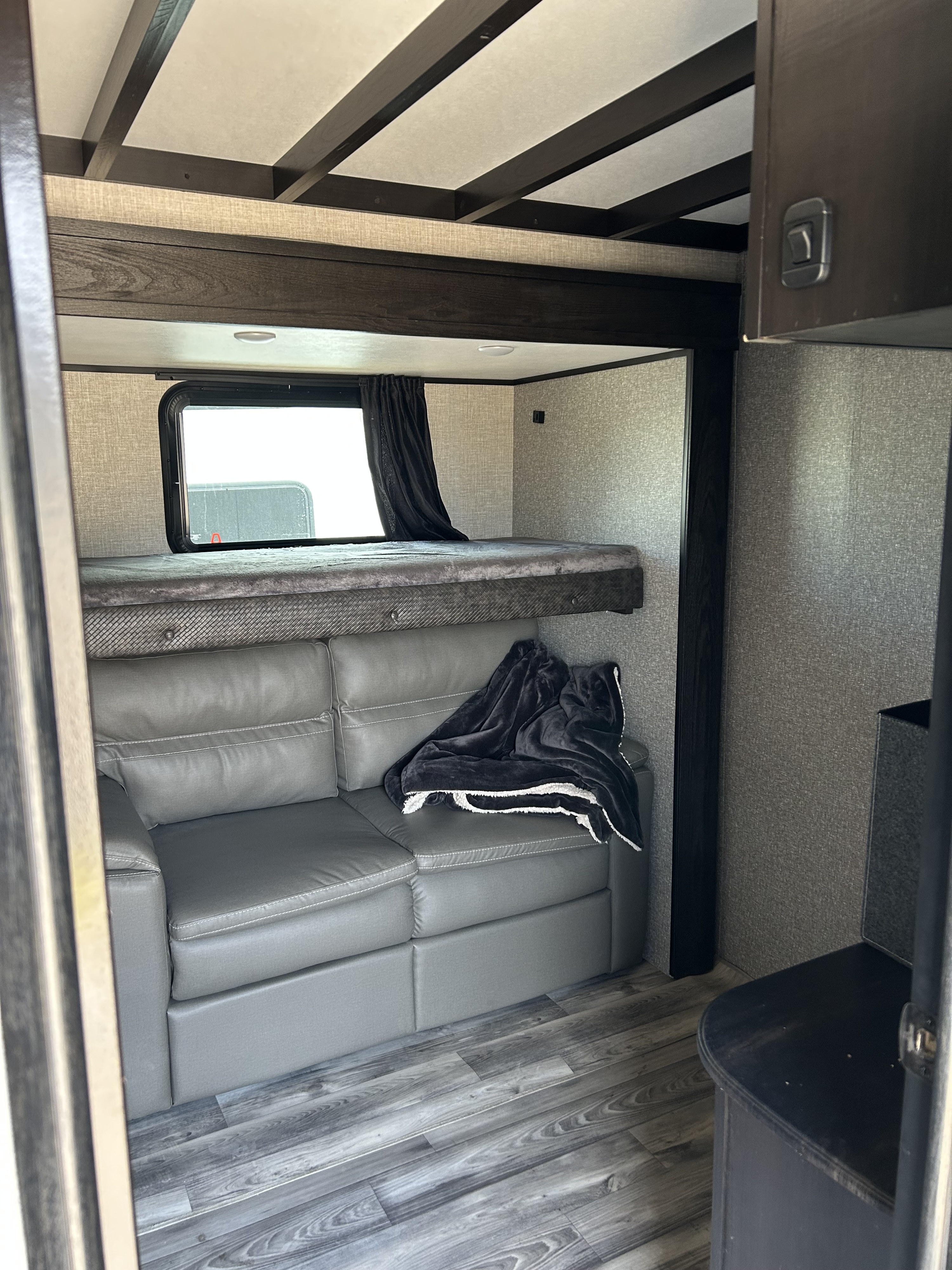 Inside an rv rental: Bunk bed over a gray sofa, dark wood accents, and modern flooring create a functional living space.. Jayco Eagle 2022