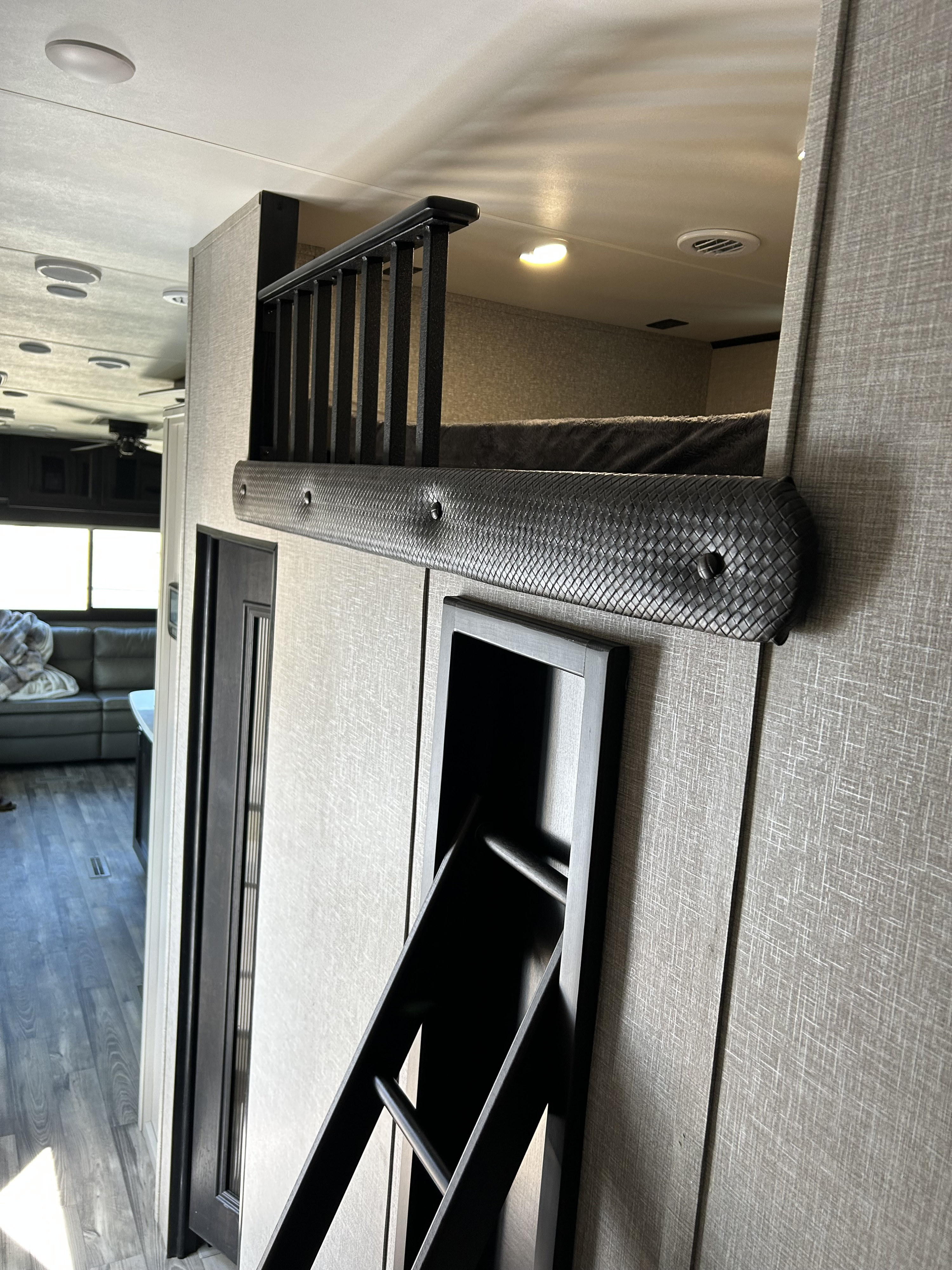 Cozy RV rental interior featuring a loft bed with a protective railing, a padded bumper, and a ladder. Modern design.. Jayco Eagle 2022