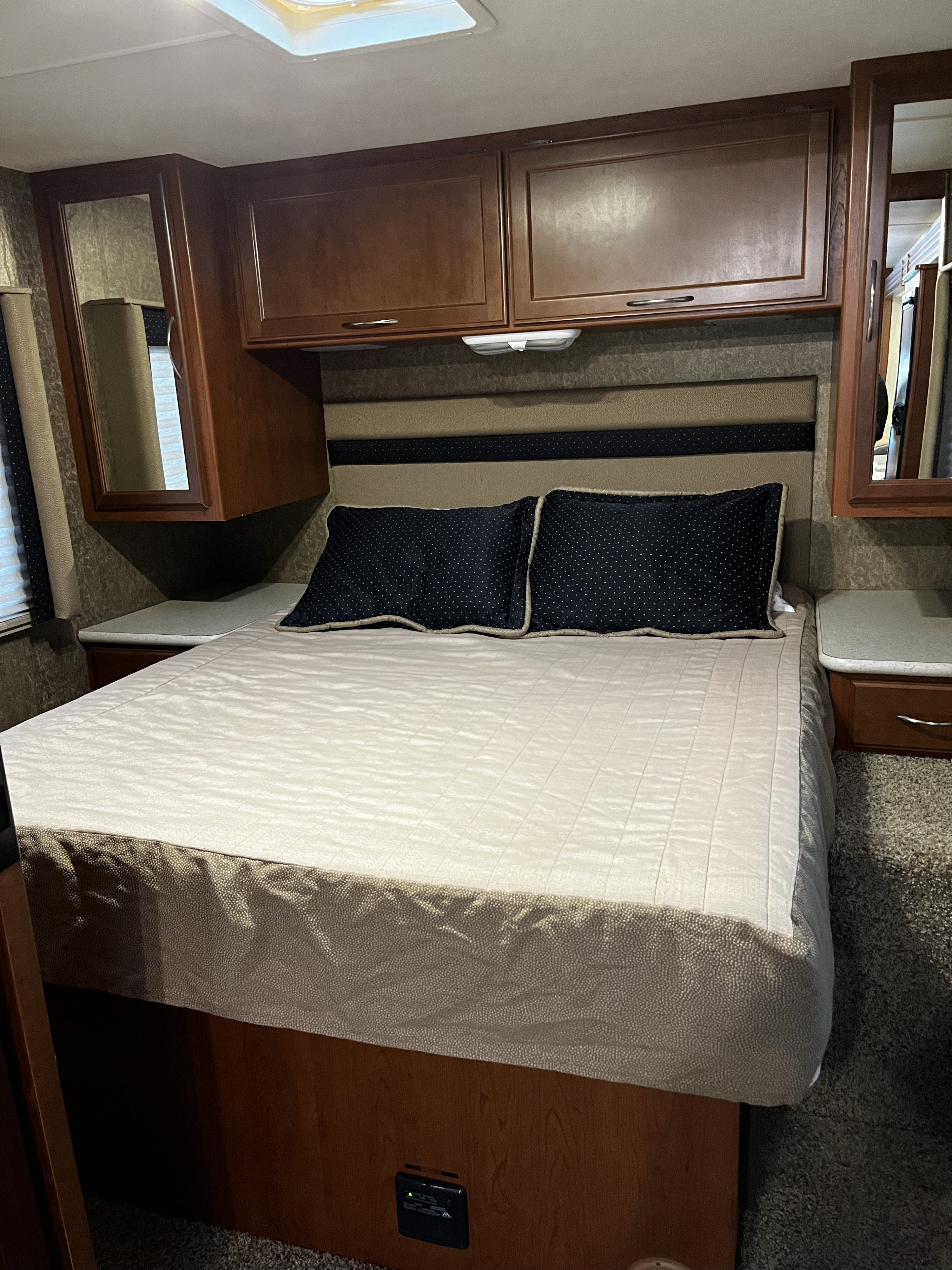 RV rental bedroom with a queen bed, upholstered headboard, overhead cabinets, and mirrored side storage.. A.C.E. A.C.E. Motorhome 2013