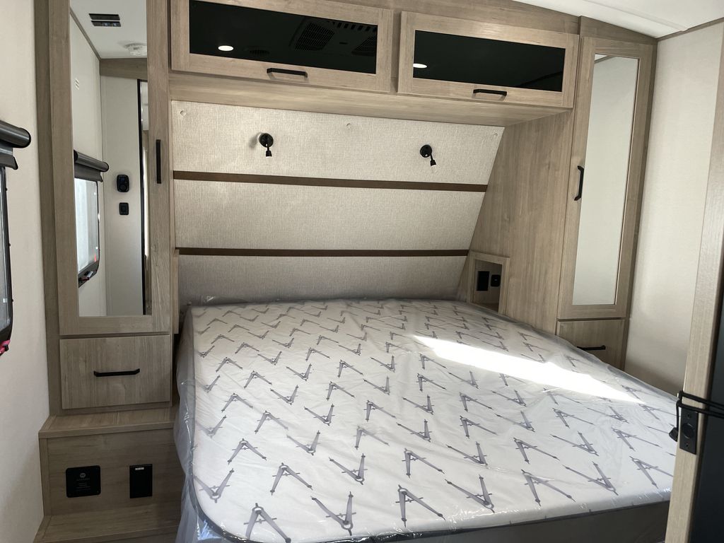 Modern RV rental bedroom, featuring a fresh mattress, overhead storage, and mirrored cabinets, designed for comfortable travel.. Grand Design Imagine 2026