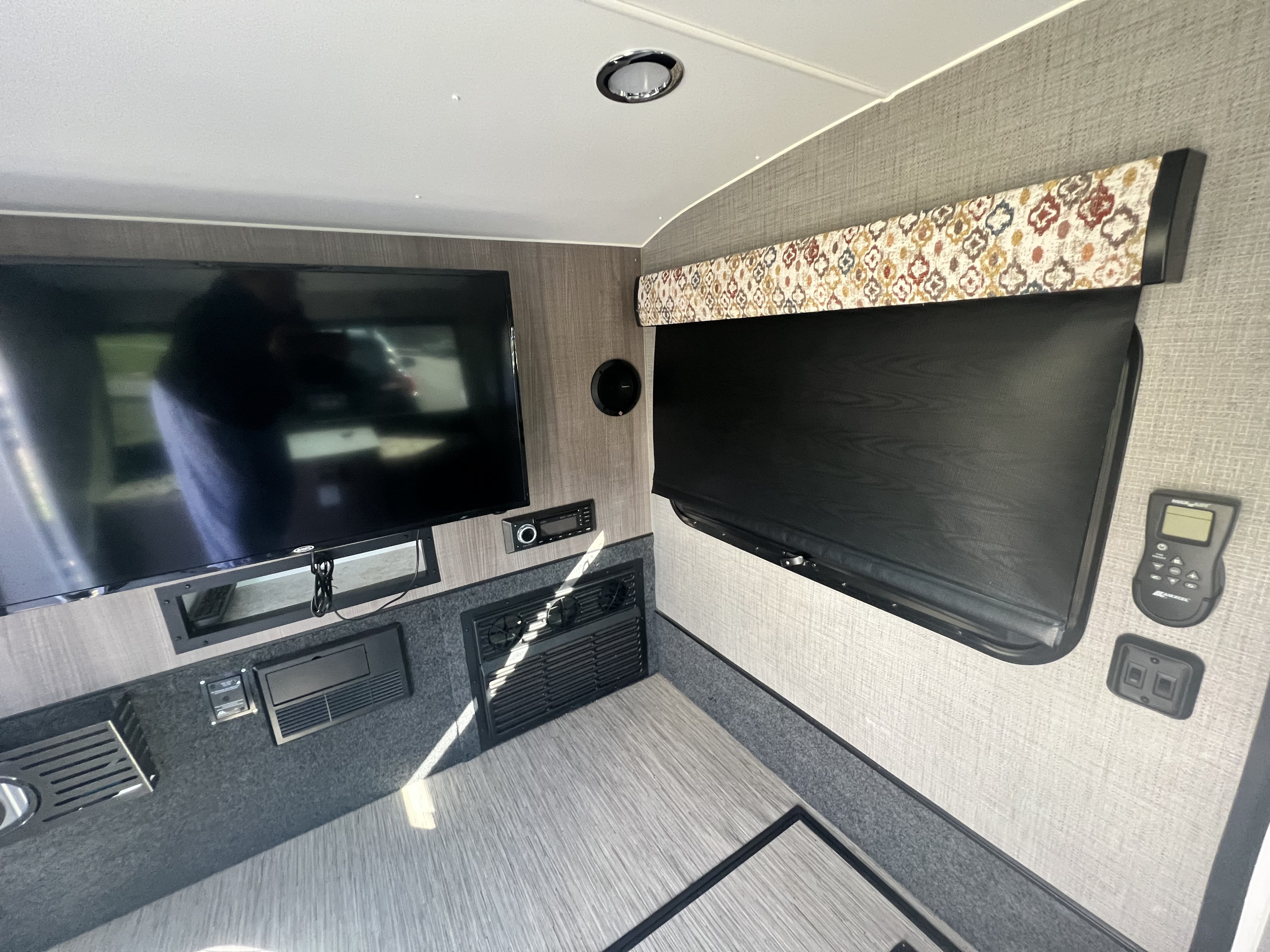 Modern rv rental interior with mounted TV, stereo, window blind, and controls for a comfortable travel experience.. InTech RV InTech RV Trailer 2018