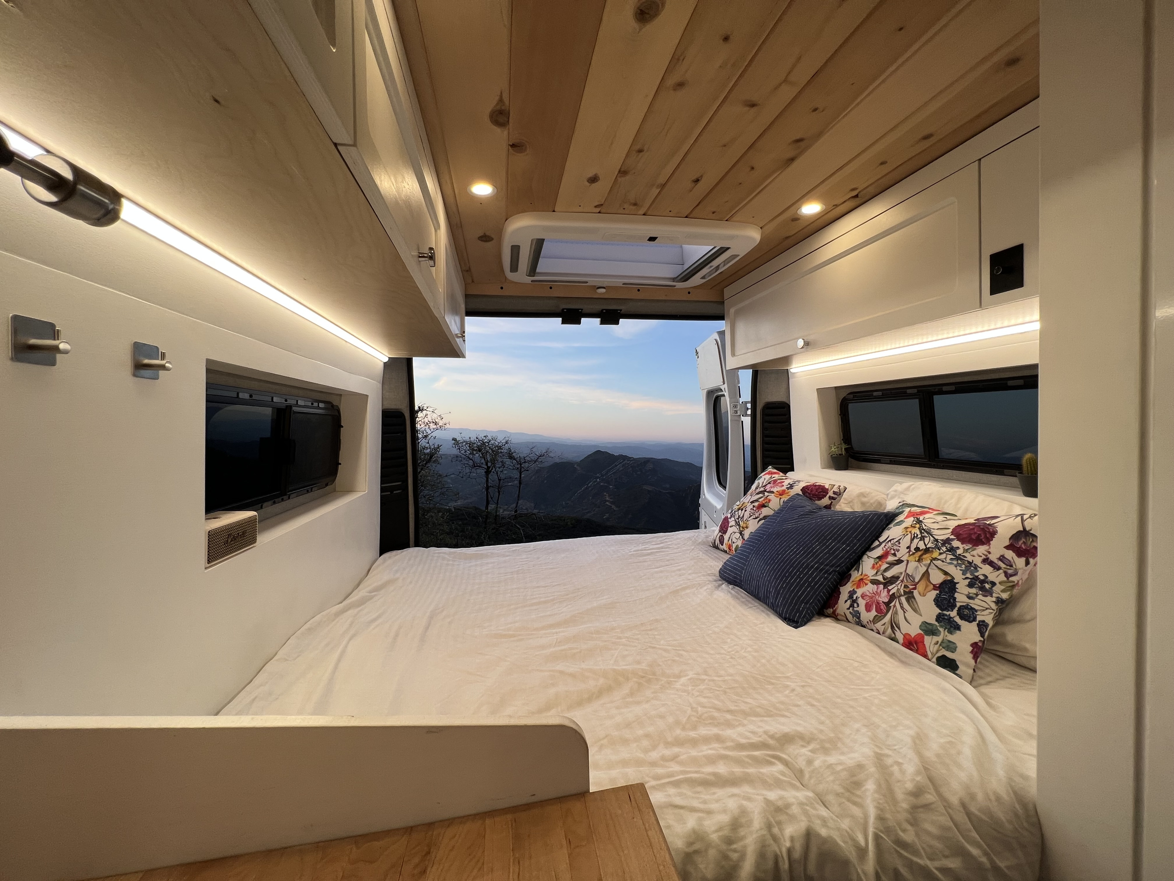 Cozy RV rental interior: a comfy bed faces an open back door with a stunning mountain view under warm lighting.. Dodge Other 2021