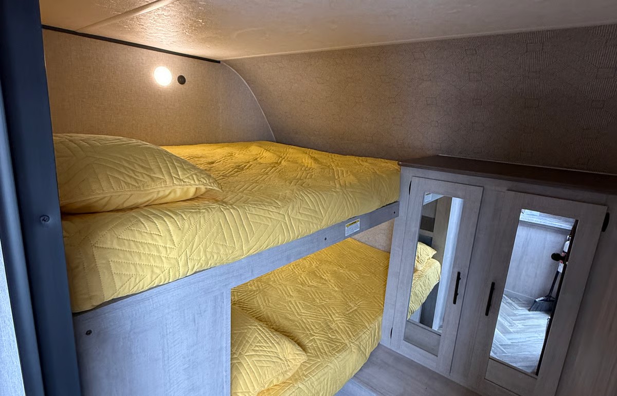 RV rental: interior view of a cozy bunk bed area with bright yellow bedding & mirrored storage for compact living.. Crossroads RV Zinger 2025