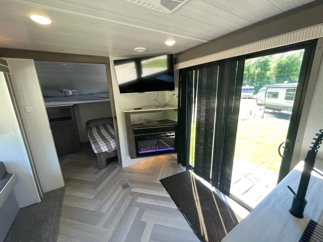 Modern rv rental interior: bunk beds, cozy electric fireplace, and a sliding door offering an outdoor view.. Forest River Salem 2023