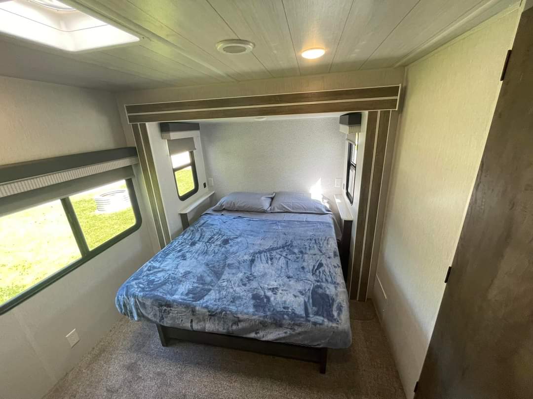 Step into comfort in this RV rental's bright bedroom, featuring a large bed & scenic windows for your next adventure.. Forest River Salem 2023