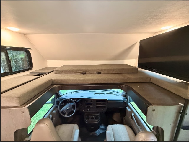 rv rental: Interior view of an RV's overhead sleeping bunk, TV, window, and driver's cockpit below.. Forest River, Inc. 2250SLE 2023