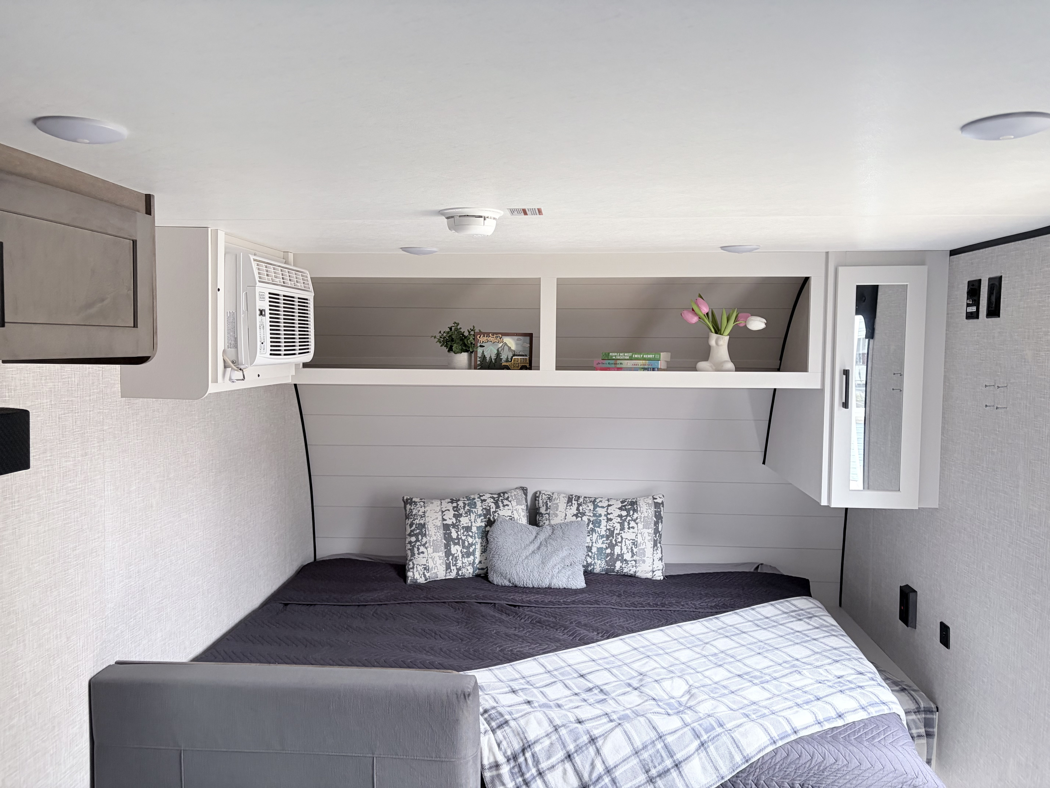 Cozy RV rental bedroom with a shiplap-style headboard, comfortable bedding, practical overhead storage, and AC unit.. Jayco Jay Flight SLX 2025