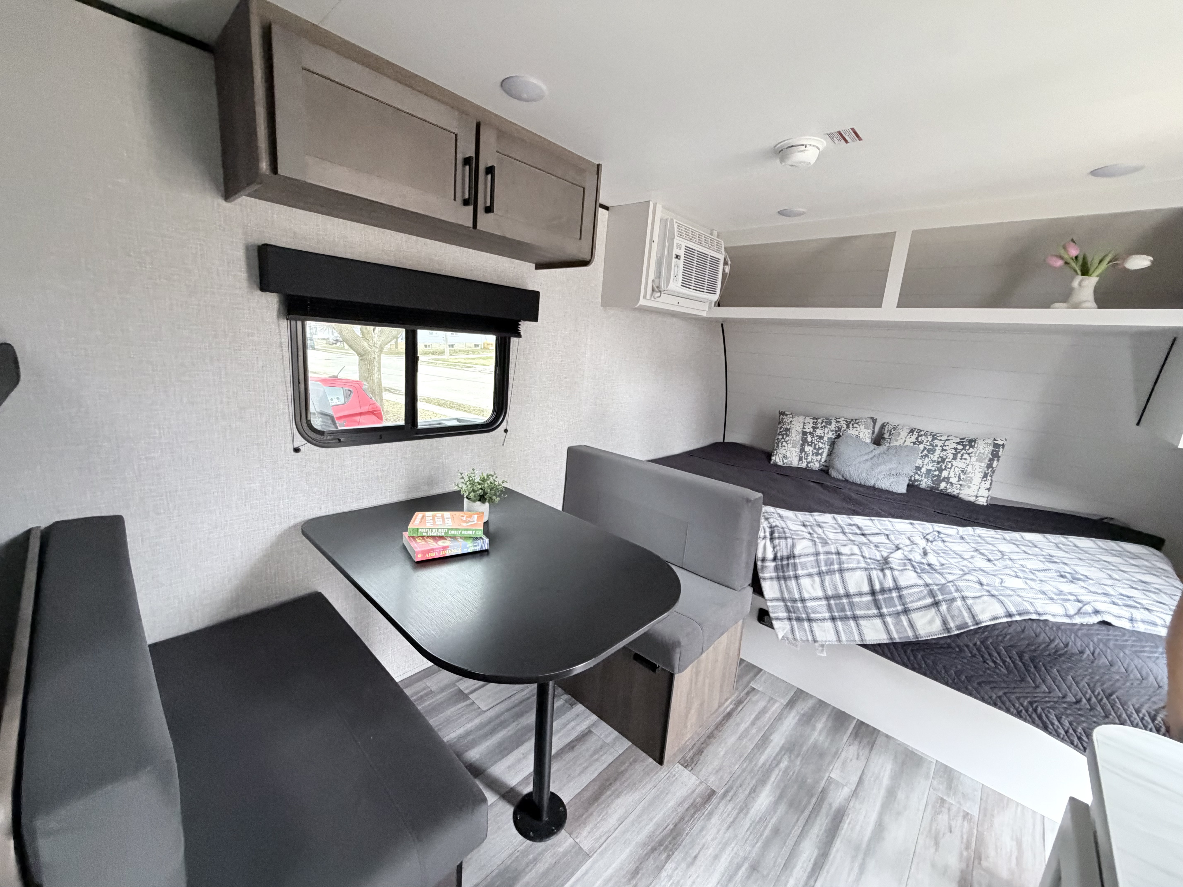 Cozy RV rental interior featuring a dining area, overhead cabinets, and a comfortable bed. Modern design, perfect for travel.. Jayco Jay Flight SLX 2025