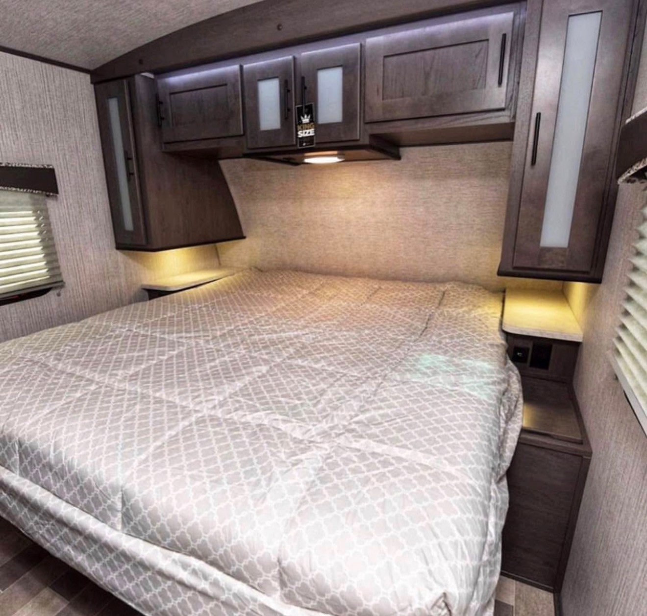 Cozy RV rental bedroom featuring a queen bed, illuminated overhead storage, and nightstands for comfortable travel accommodation.. Cruiser RV Embrace Ultra Lite 2019