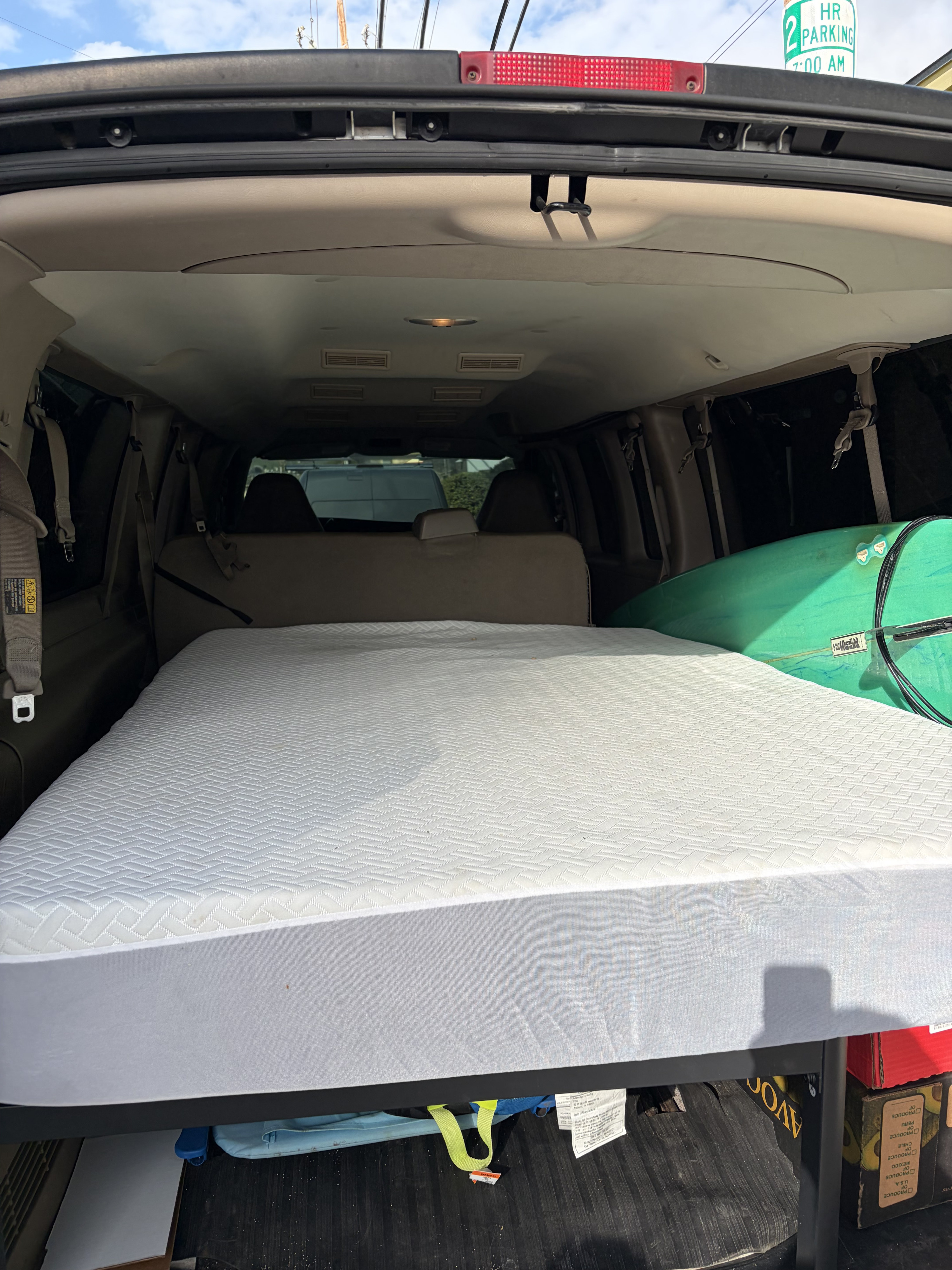 Cozy RV rental setup in a converted van, featuring a mattress, surfboard, and organized storage for travel.. Chevrolet Chevrolet Express 3500 Extended 2009