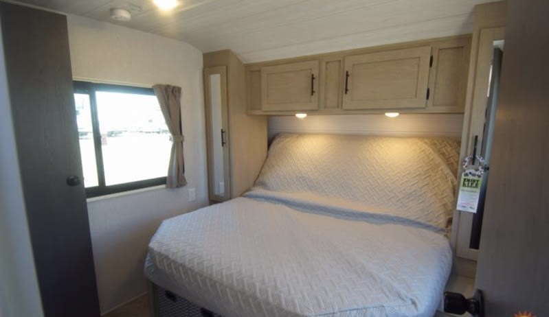 This compact RV rental bedroom features a cozy bed, overhead storage, and a window for natural light. Ideal for travel.. Forest River Salem Cruise Lite 2024
