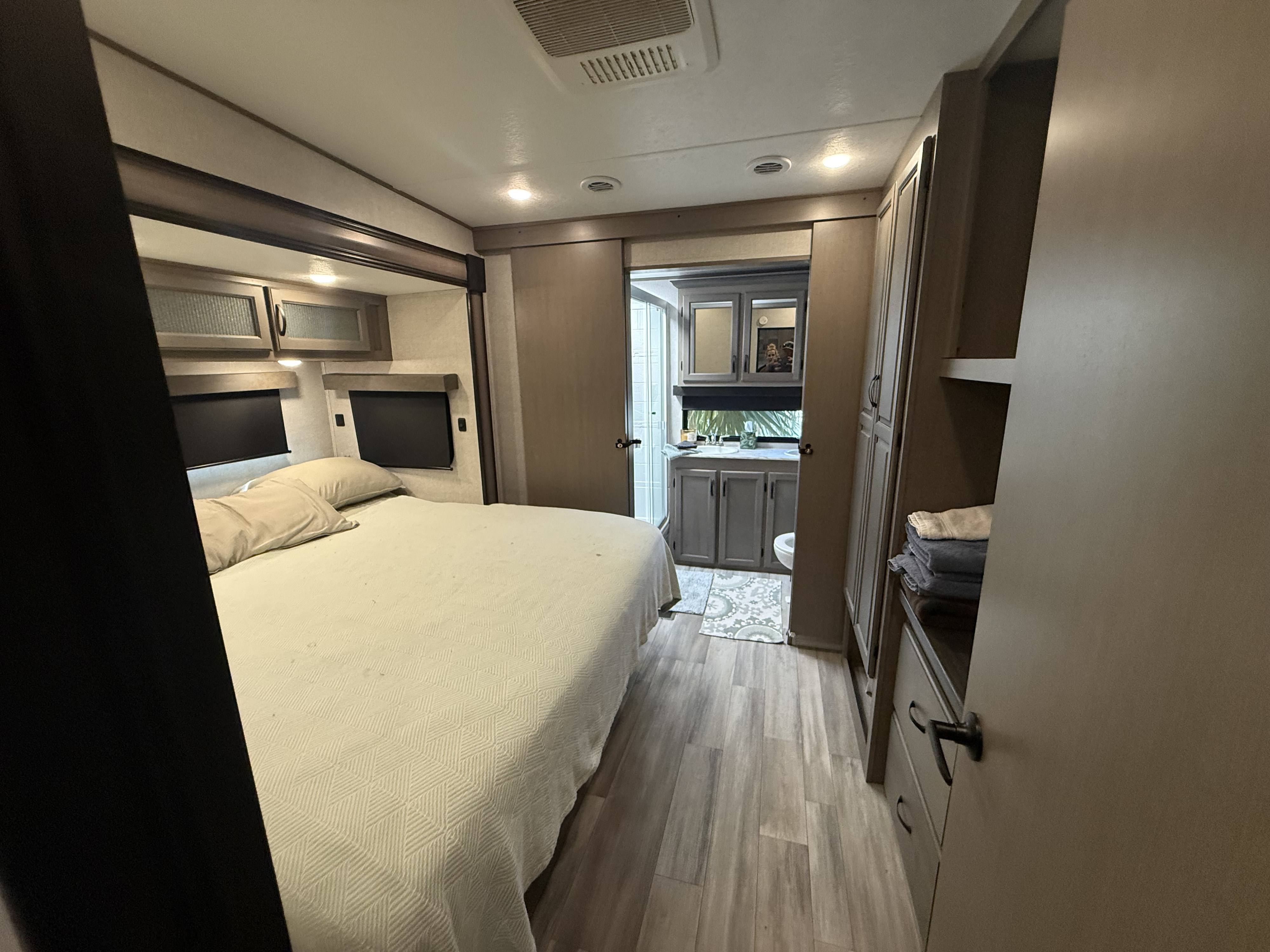 RV rental bedroom with a cozy bed and attached bathroom, featuring a vanity and shower, offering comfortable living space.. Forest River Coachmen Chaparral 2023