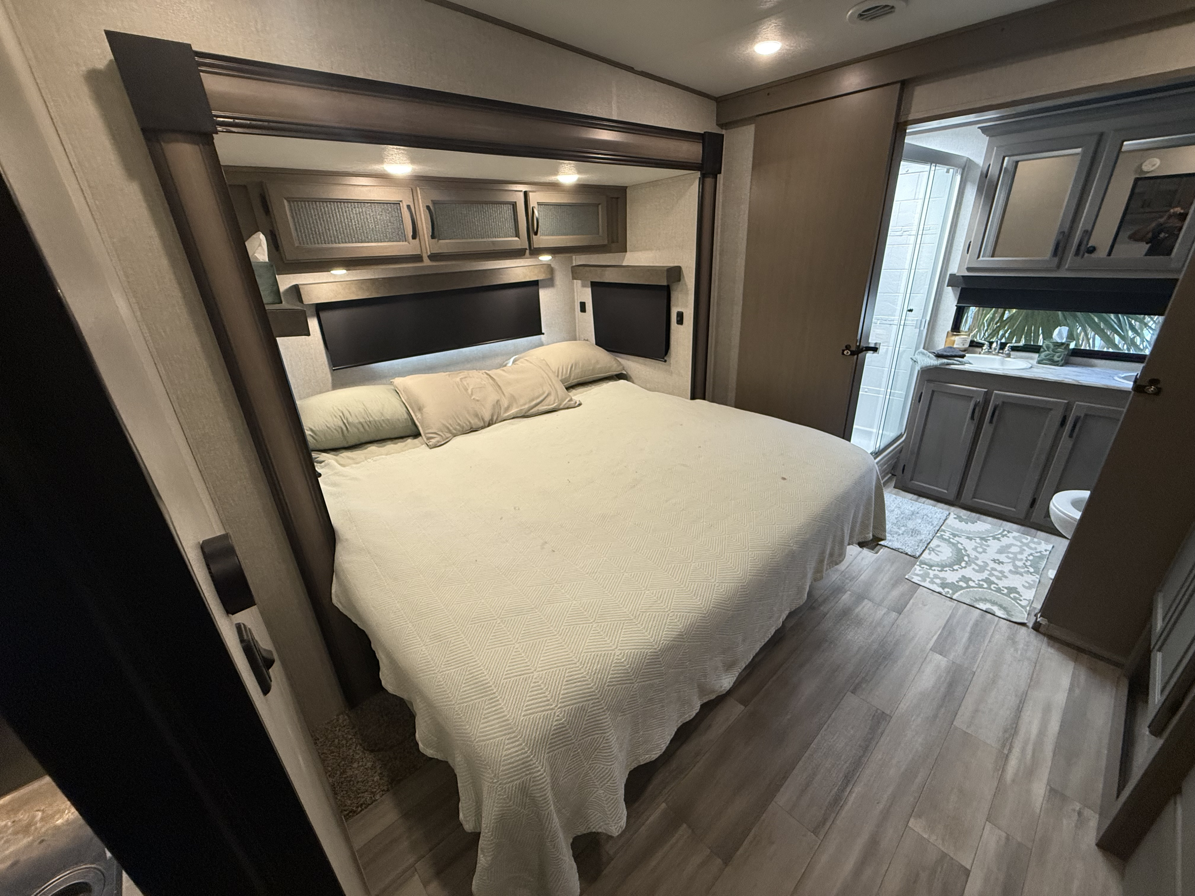 Comfortable RV rental bedroom with a large bed, overhead storage, and an attached modern bathroom. Perfect for road trip relaxation.. Forest River Coachmen Chaparral 2023