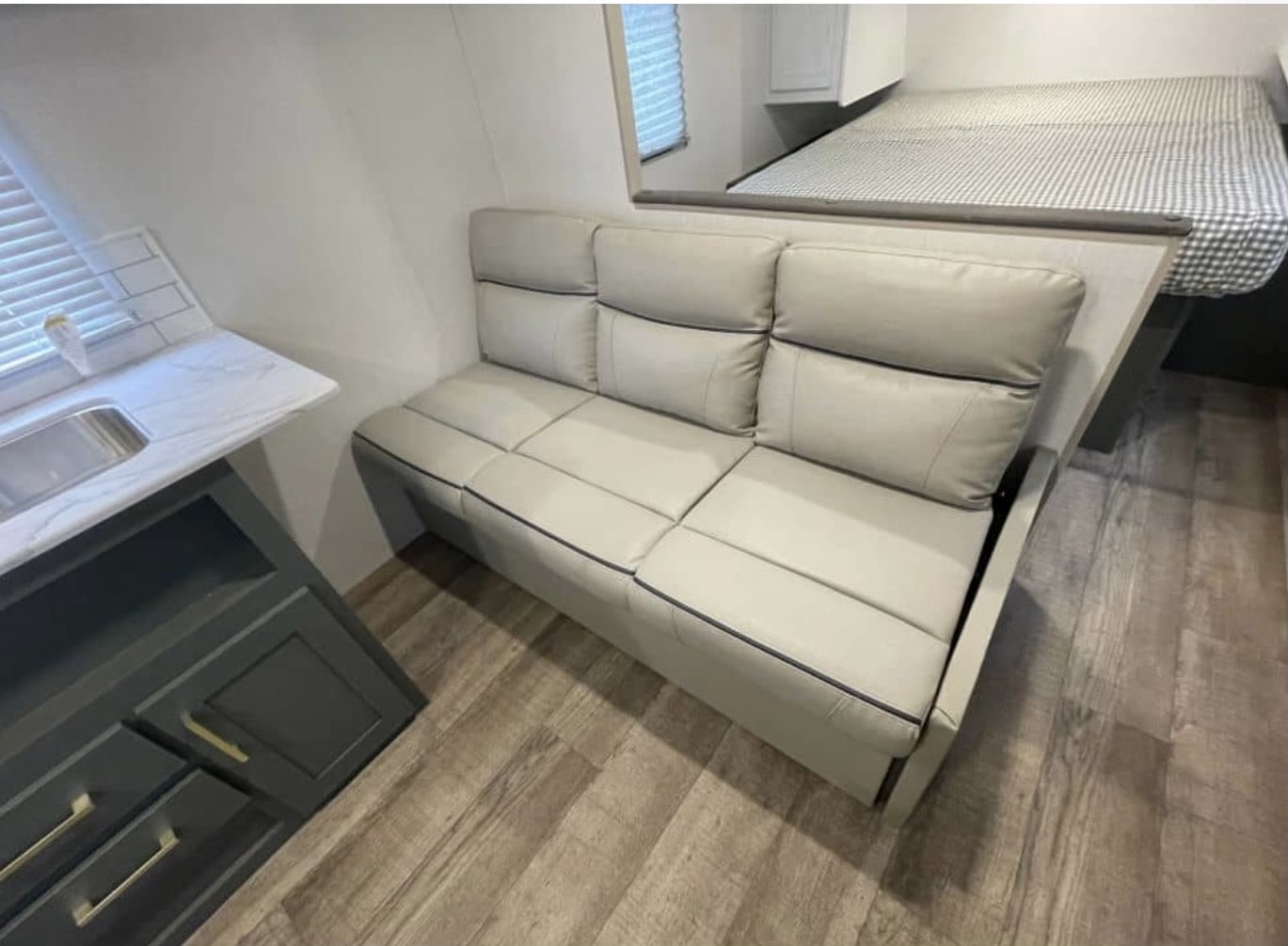 Cozy RV rental interior with light gray dinette seating, a compact kitchen with sink, and a raised bed area.. Heartland RVs Eddie Bauer 2024