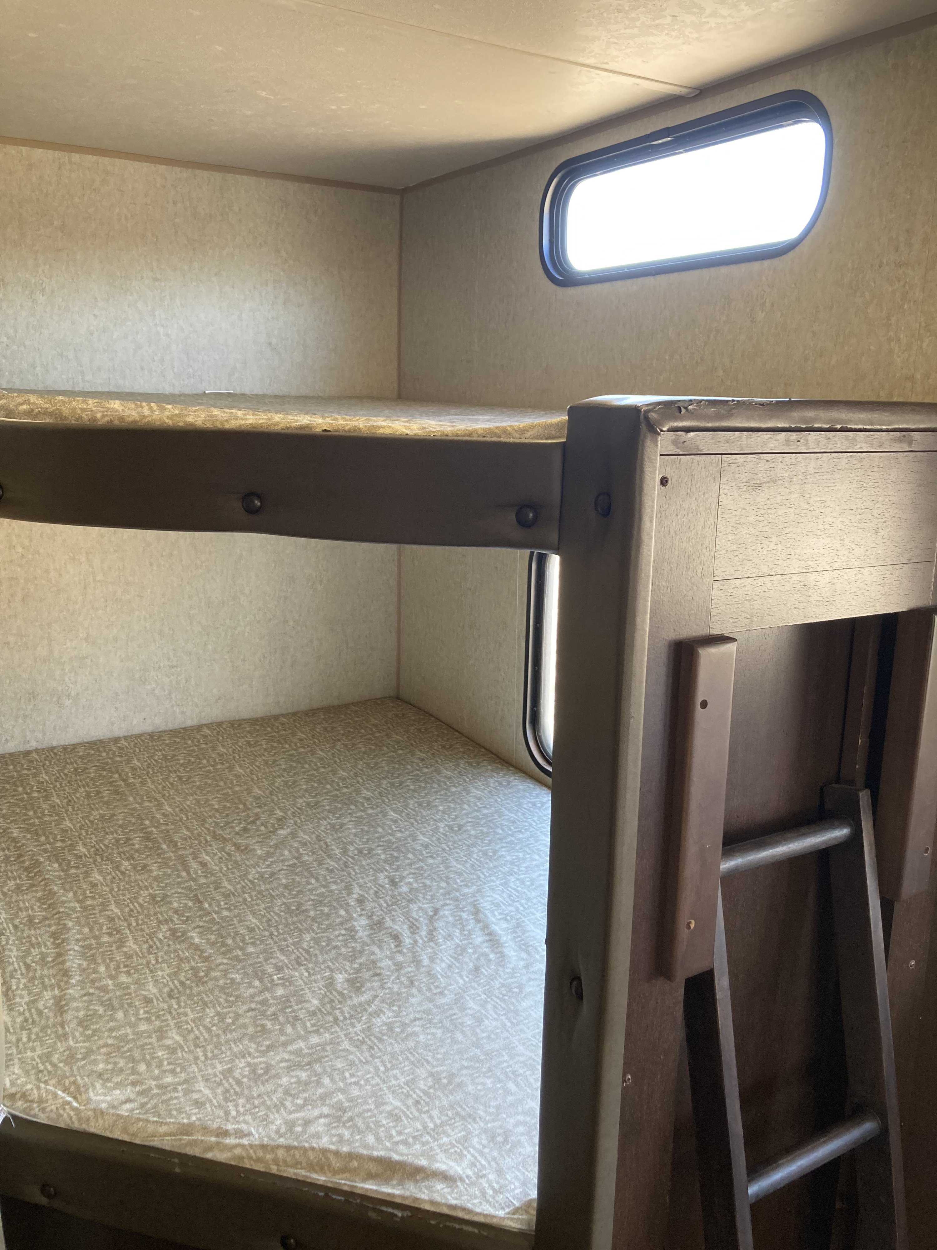 RV rental bunk beds in a cozy interior, with a bright window & ladder. Ideal for family adventures.. Forest River Cherokee 2016