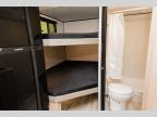 Compact RV rental interior featuring bunk beds, a refrigerator, and a compact bathroom with a toilet and shower.. Keystone RV Coleman 2025