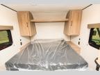 Cozy RV rental sleeping area features a bed with overhead shelf and storage cabinets, perfect for your next road trip adventure.. Keystone RV Coleman 2025