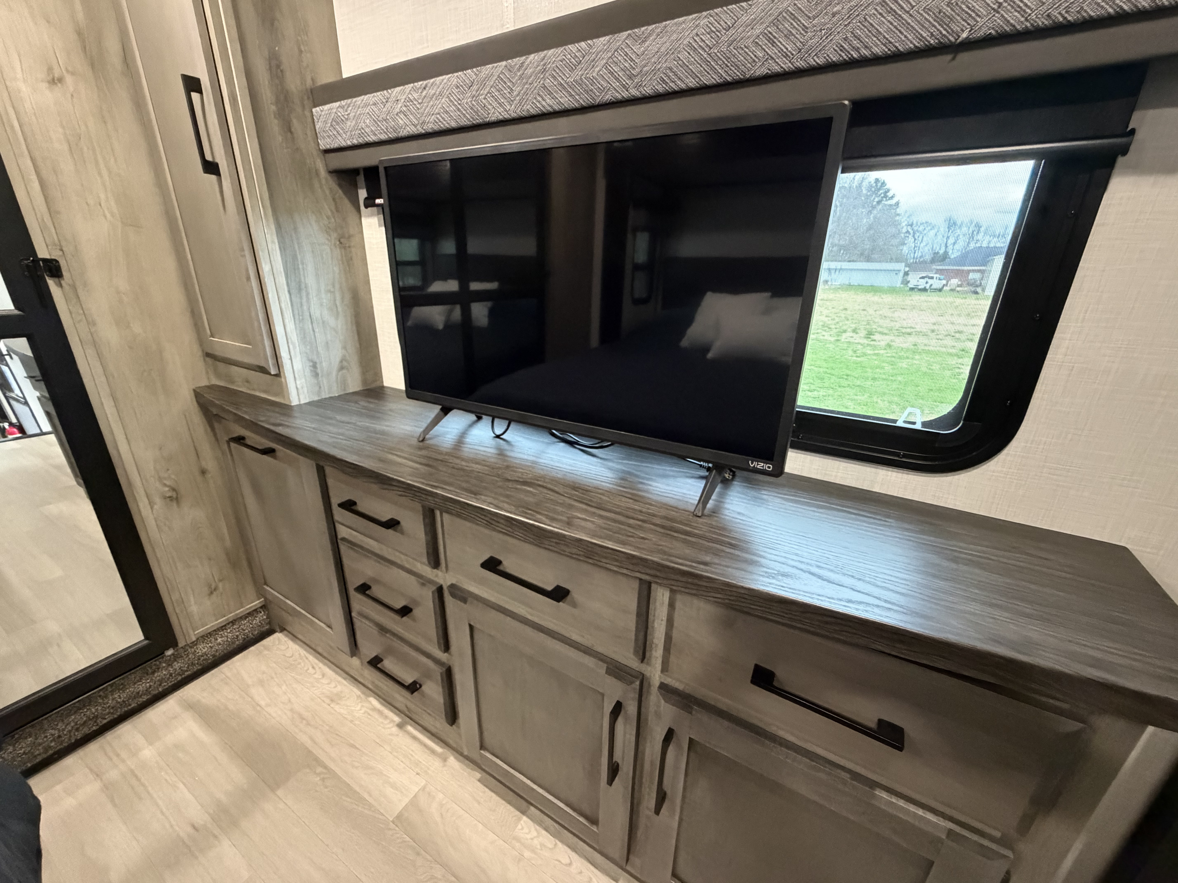 This RV rental features a cozy bedroom/living area with a TV on a stylish dresser, ample storage, and a bright window.. Durango Durango Fifth Wheel 2023