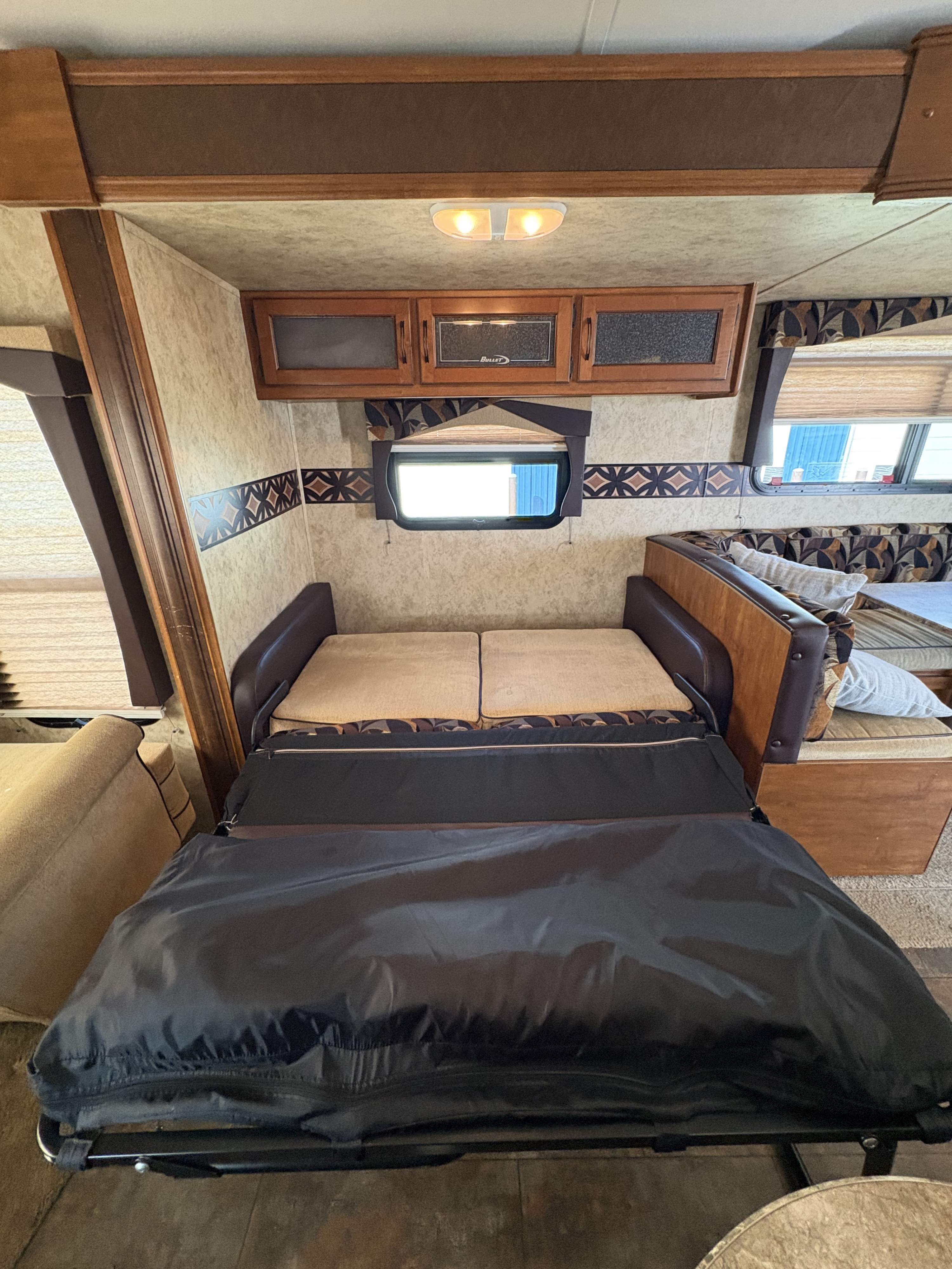 Cozy RV rental interior with a fold-out sofa bed, overhead cabinets, and patterned walls, perfect for travelers.. Keystone RV Bullet Ultra Lite 2011