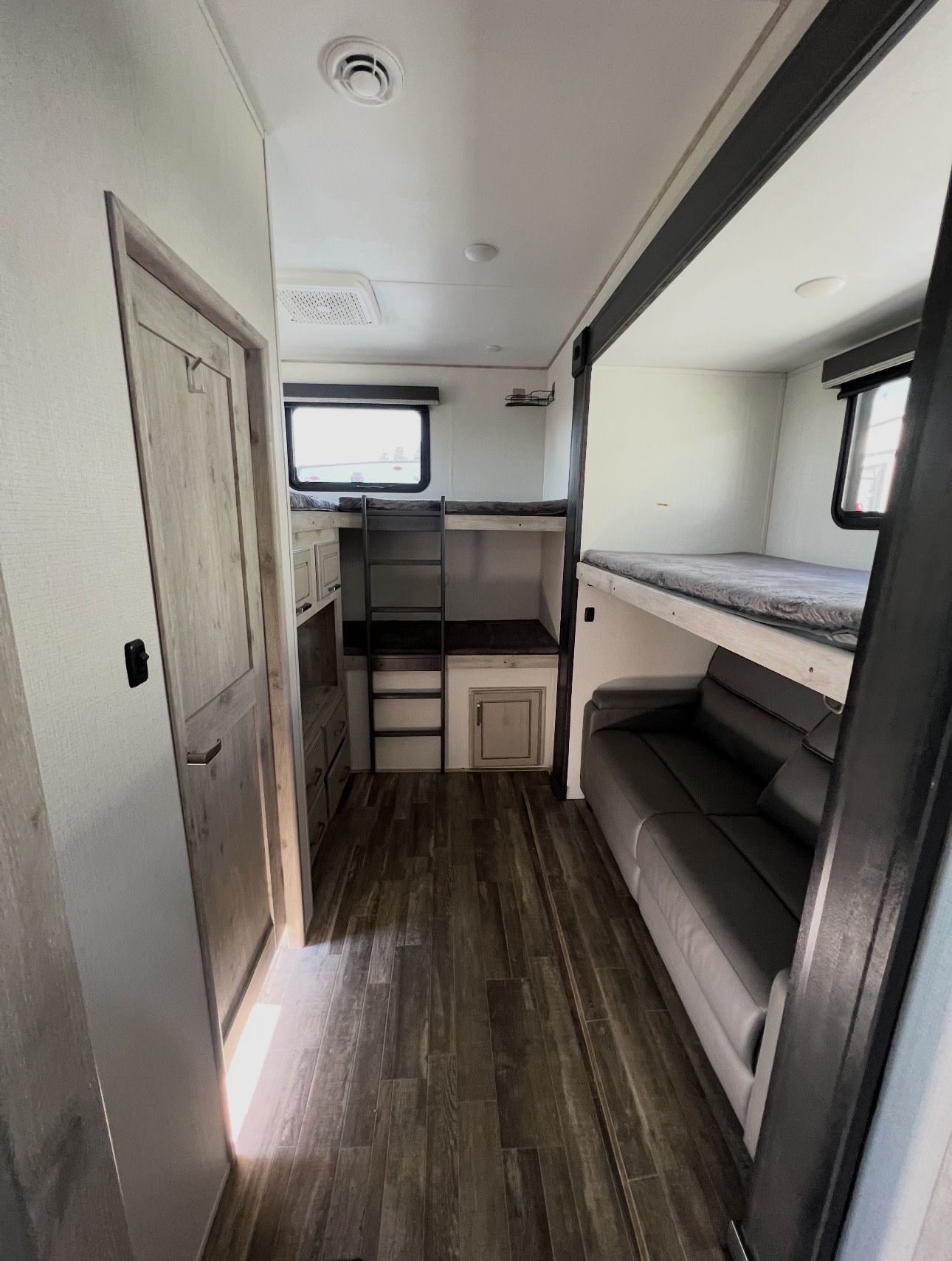 Spacious RV rental interior featuring bunk beds, a cozy sofa, and wood-look flooring for family adventures.. Keystone RV Avalanche 2022