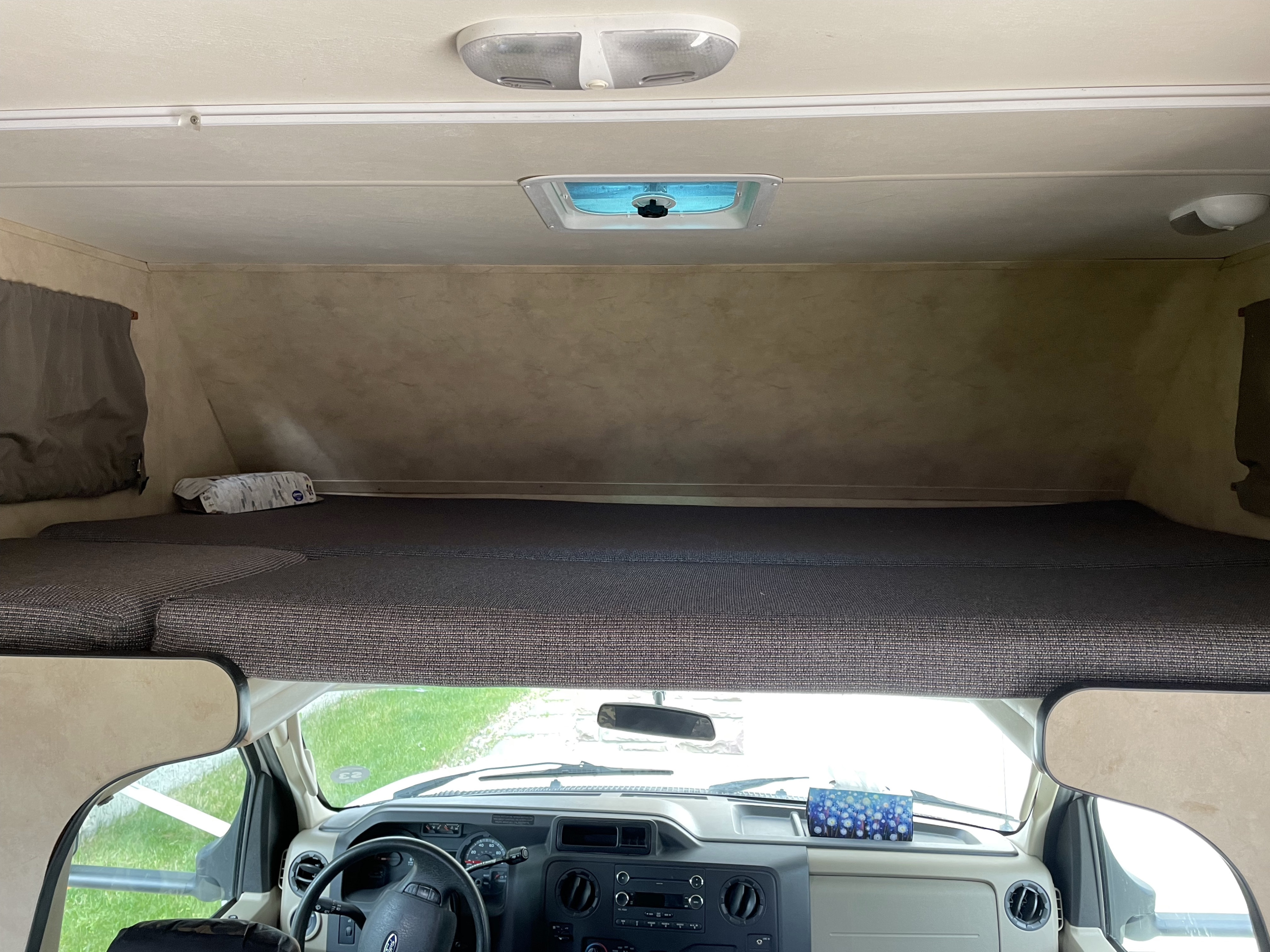Interior of an RV rental: Looking up at the cozy cab-over bunk sleeping area above the driver's dashboard.. Majestic Leisure Craft Cutaway 2012
