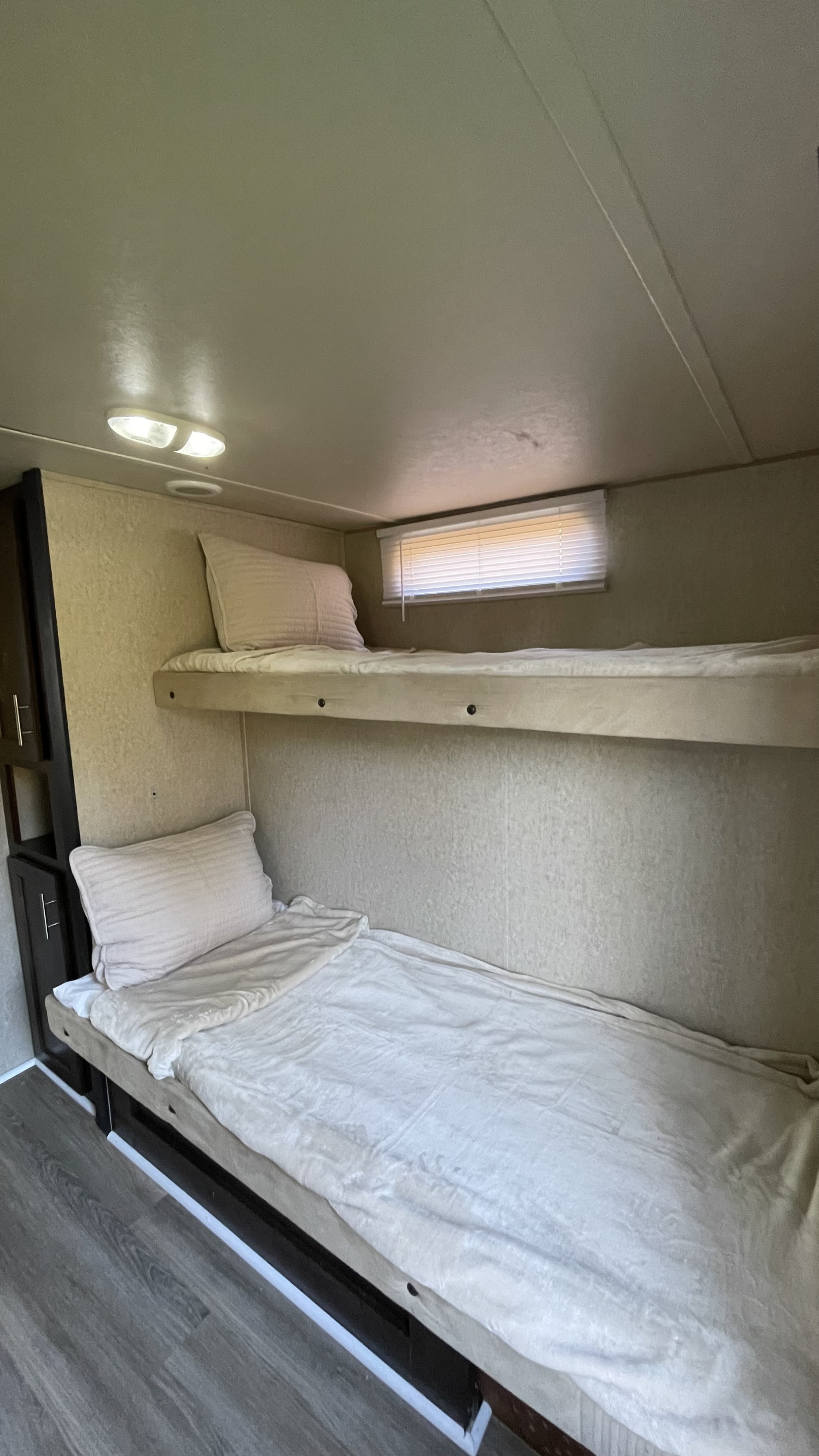 Inside an RV rental, showing cozy bunk beds, a window with blinds, and built-in cabinetry.. Forest River Cherokee 2016