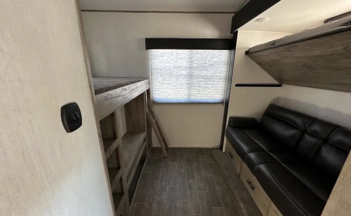 Cozy RV rental interior with bunk beds, a sofa, storage, and a window for comfortable travel.. Forest River Forest rivee 2022