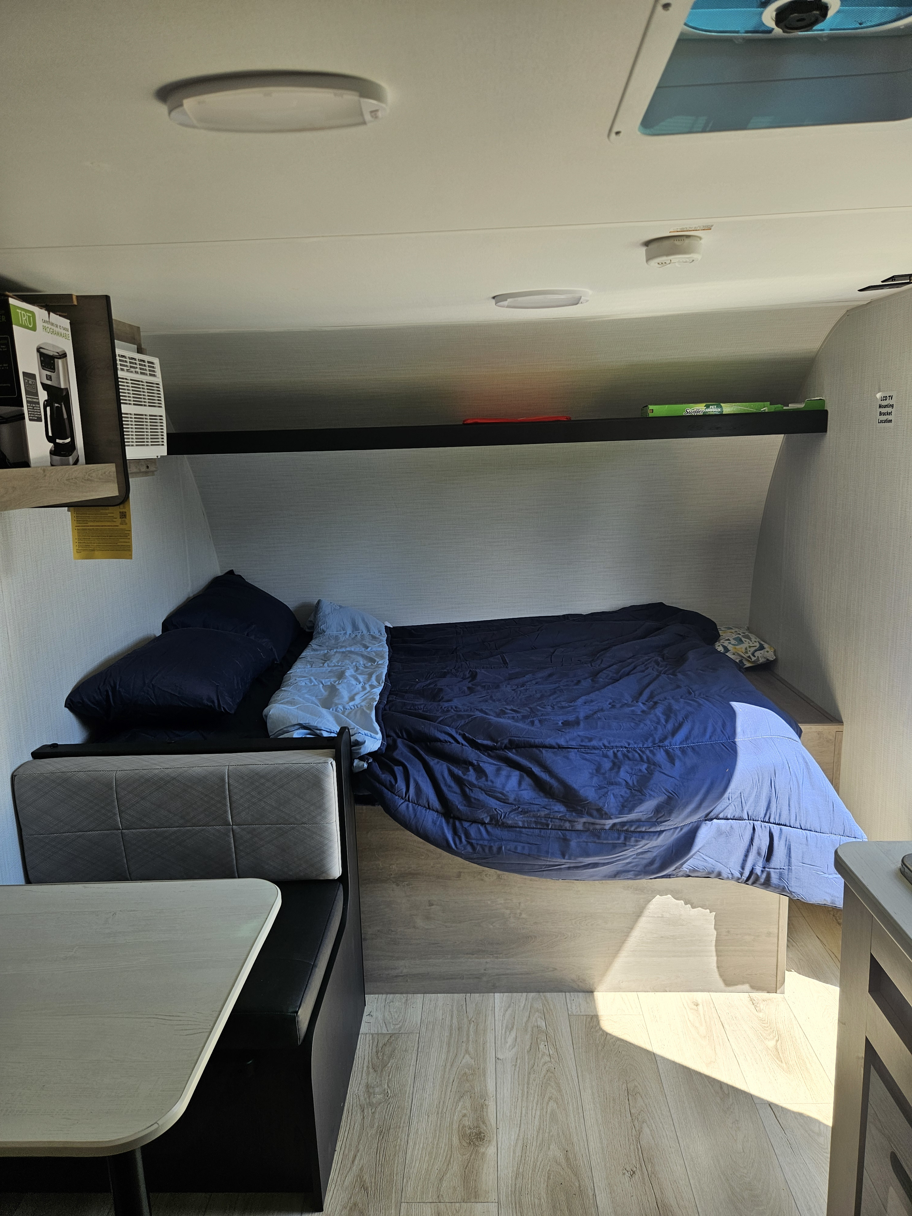 RV rental interior features a comfortable bed with blue bedding, a dinette, and warm sunlight on the floor.. Cruiser Rv Avenir 17BHC 2025