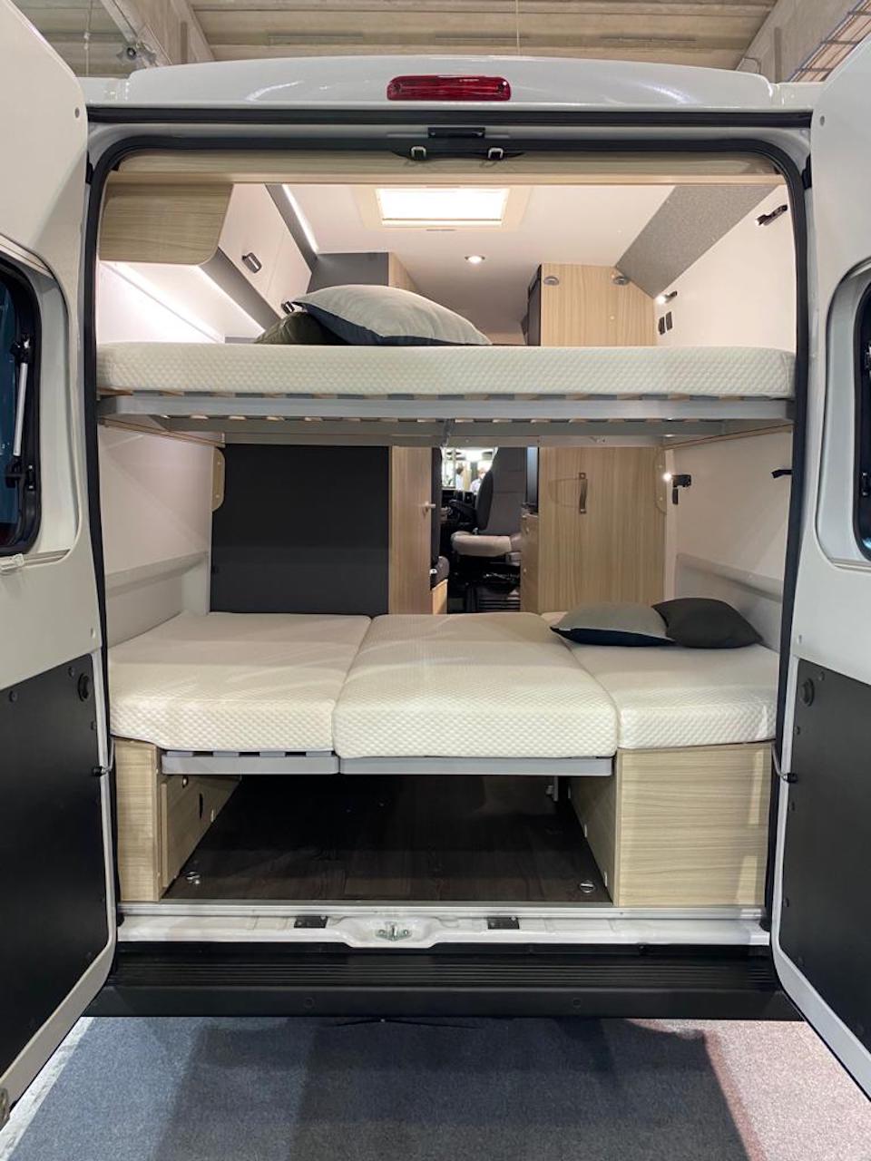 View inside an RV rental camper van from the rear. Two beds, a top bunk & a lower foldable bed with storage, offer compact sleeping.. SunLiving V 60 SP2026 2026