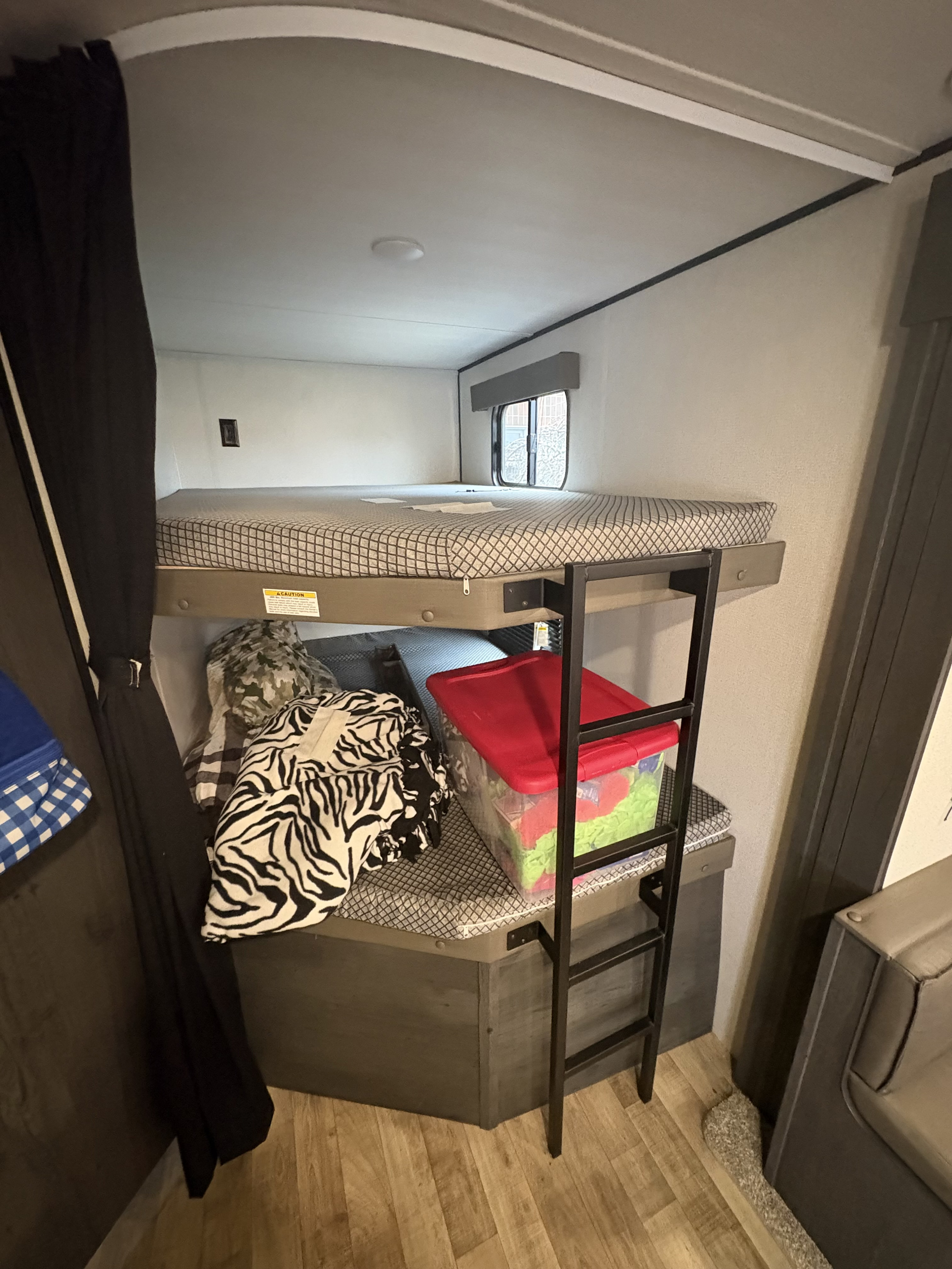 RV rental interior: bunk beds with a window on top, and a lower bunk featuring storage, a ladder, and privacy curtain.. Keystone RV Hideout 2022