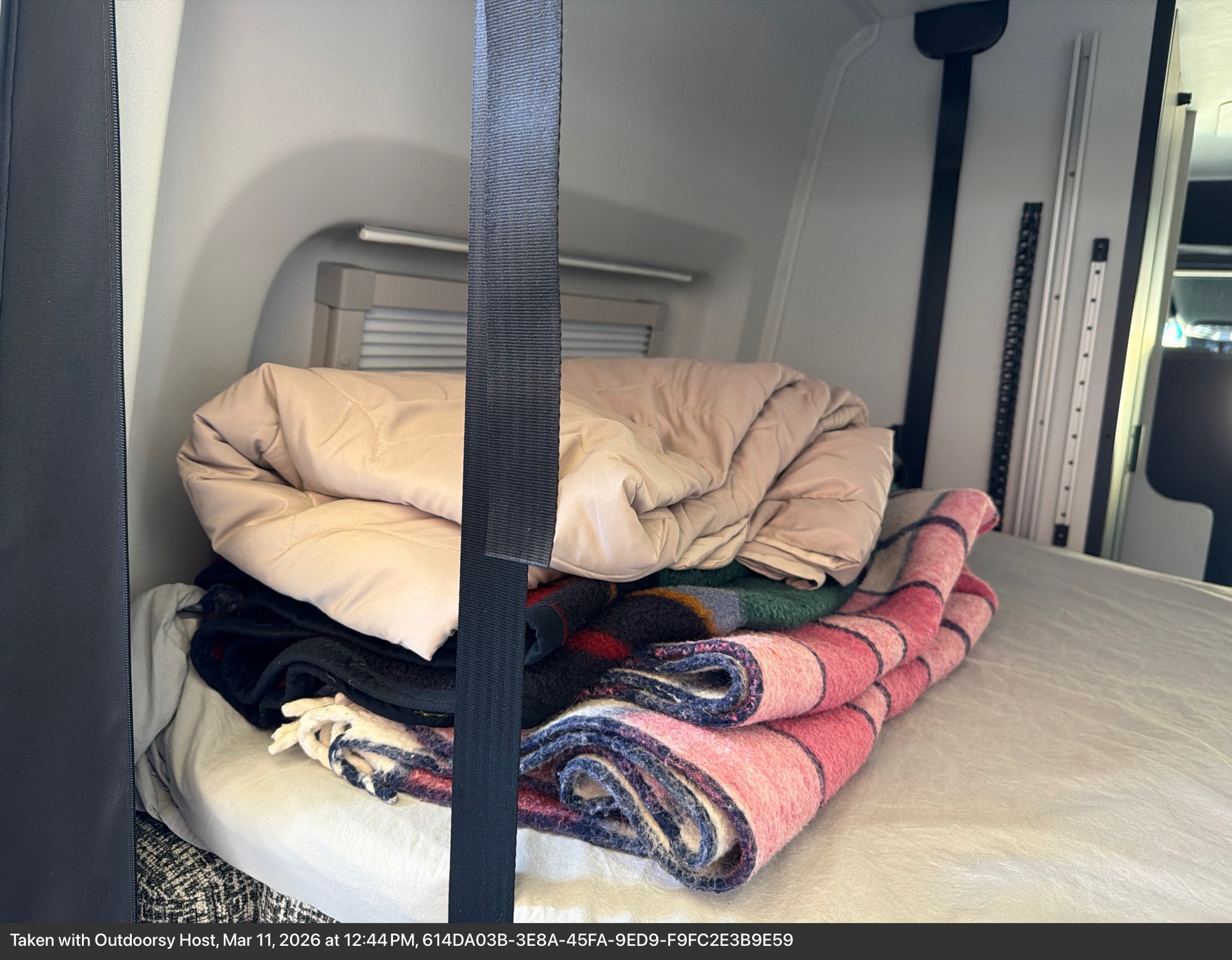 Stacked blankets & jacket on an RV rental bed, a cozy setup for your adventure.. Tiffin GH1 2025