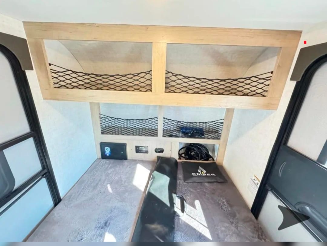 RV rental interior: cozy sleeping areas with overhead storage nets and a control panel. Ideal for compact travel.. Ember E Series Spark LE 2026