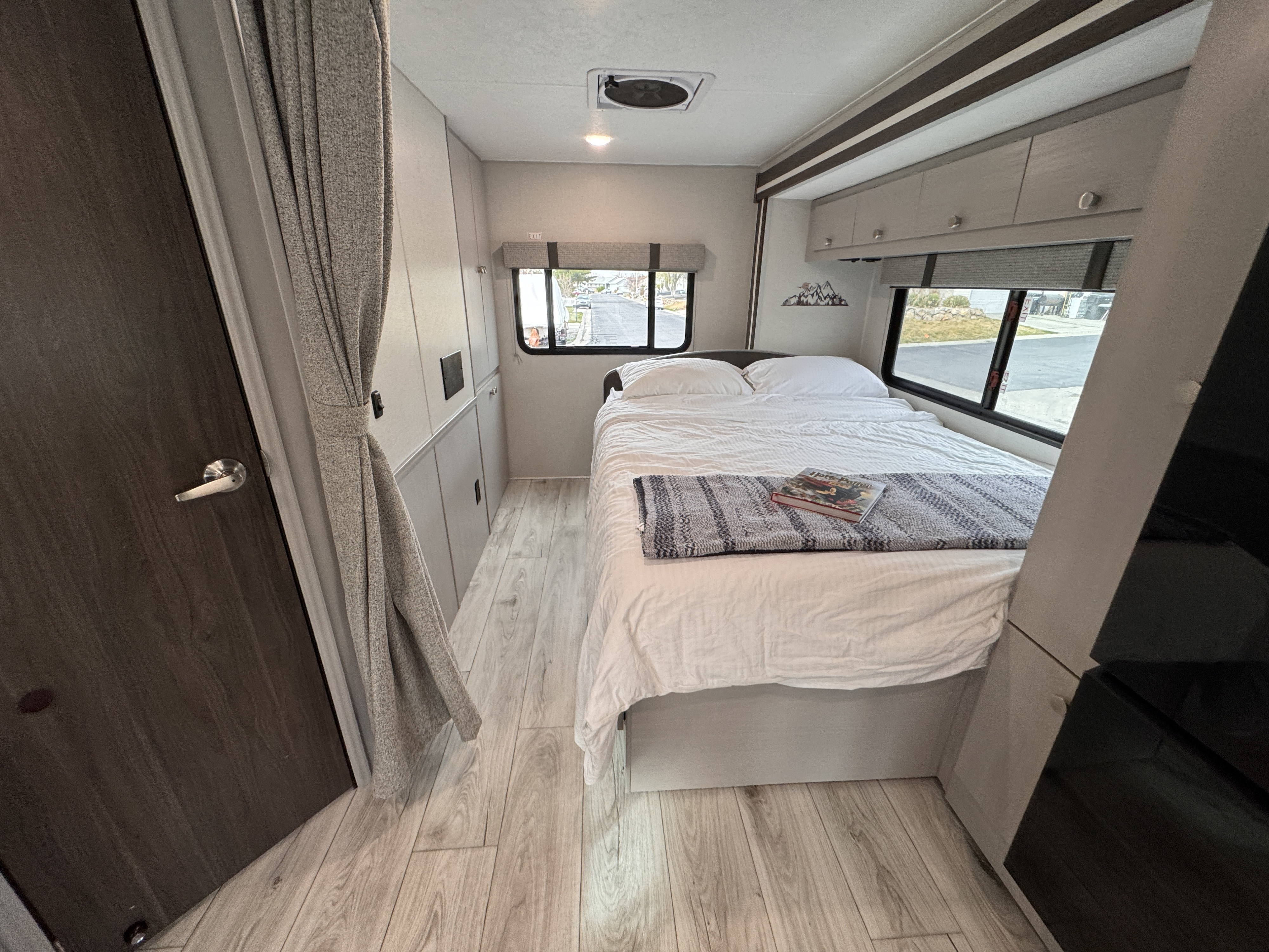 Inside a modern rv rental: a cozy bedroom with a neatly made bed, windows, and overhead storage for comfortable travel.. Forest River Coachmen Freelander 2026